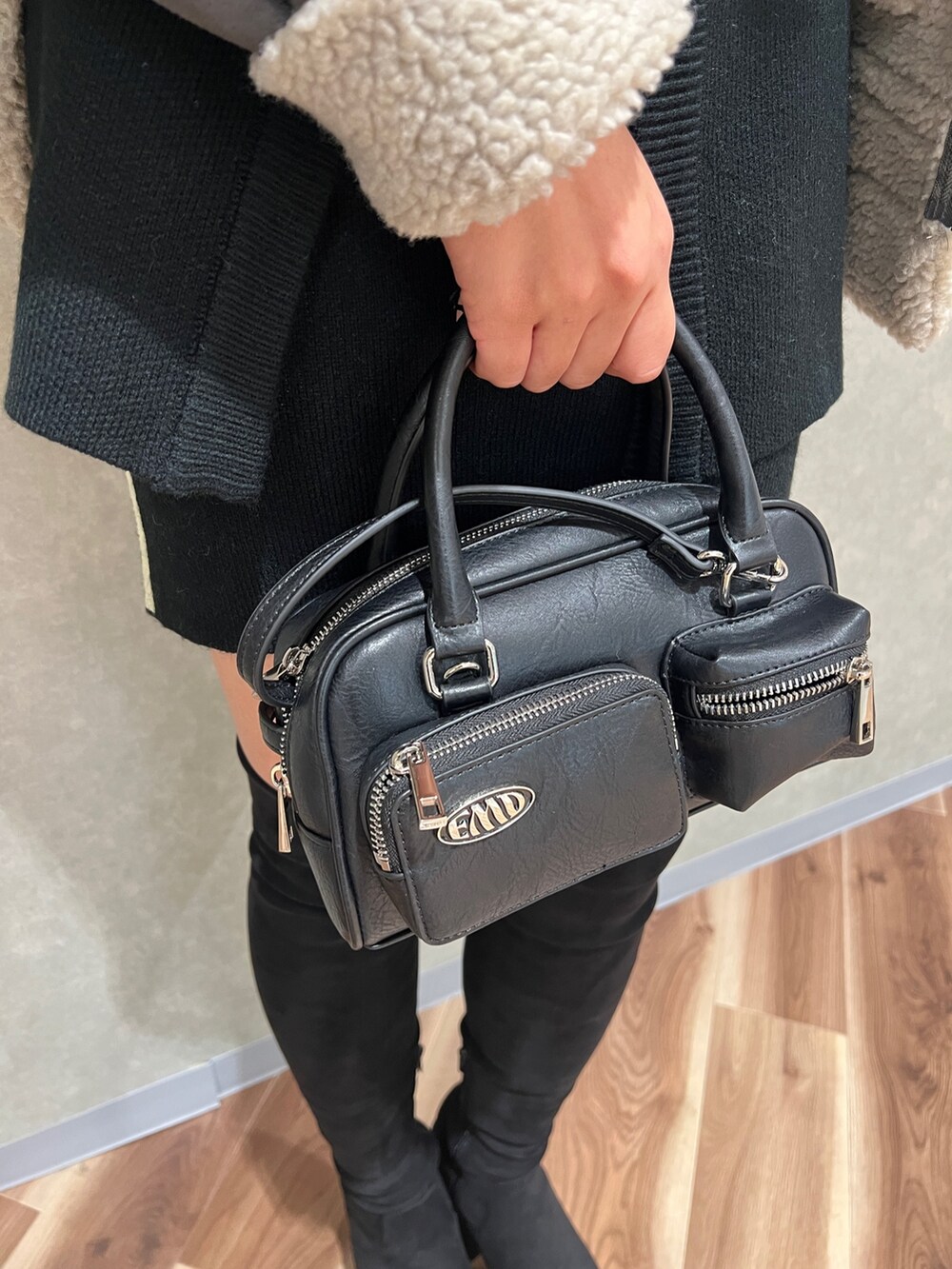 グレー系のムートンコート、ブラック系のカーディガン/ボレロ、ブラック系のスカートを着用したレディースの秋コーディネートの8枚目の写真