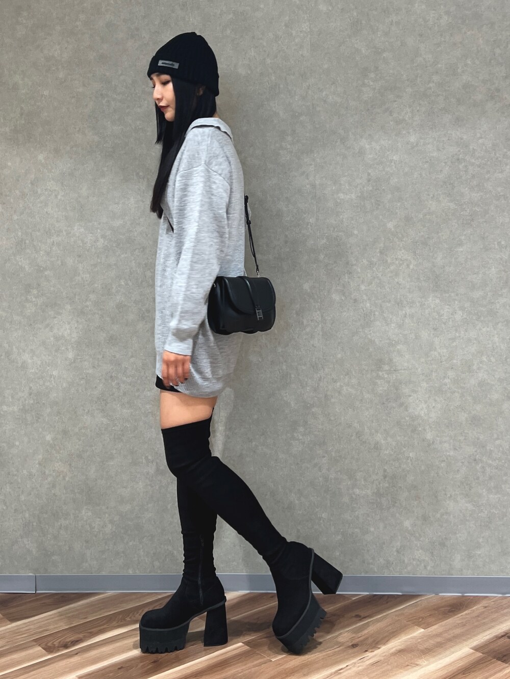 グレー系のワンピース、ブラック系のスカート、ブラック系のブーツを着用したレディースの秋コーディネートの2枚目の写真
