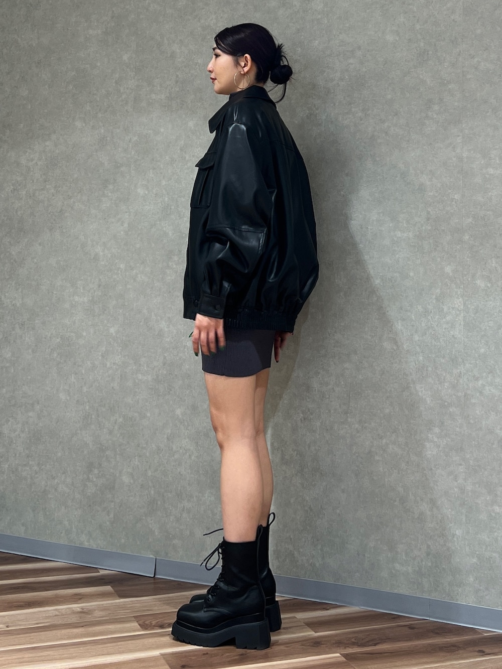 グレー系のワンピース、ブラック系のブルゾン、ブラック系のブーツを着用したレディースの冬コーディネートの2枚目の写真