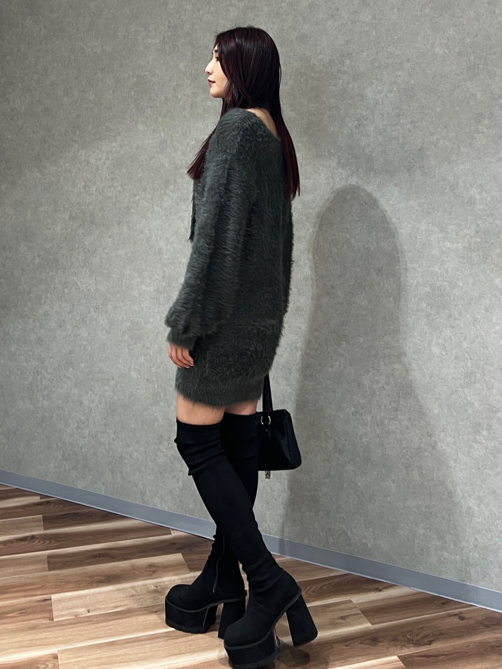 グレー系のワンピース、ブラック系のショルダーバッグ、ブラック系のブーツを着用したレディースの秋コーディネートの4枚目の写真