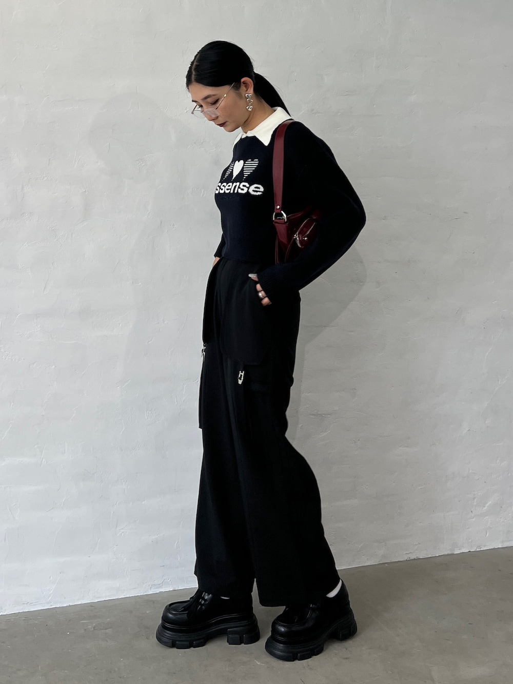 ブラック系のニット/セーター、ブラック系のその他パンツ、レッド系のハンドバッグを着用したレディースの秋コーディネートの3枚目の写真