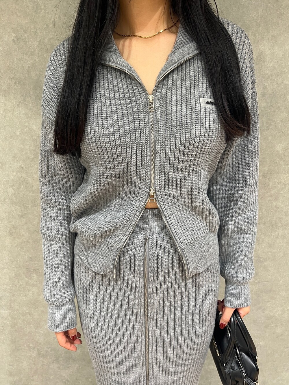 グレー系のスカート、グレー系のニット/セーター、ブラック系のブーツを着用したレディースの冬コーディネートの5枚目の写真