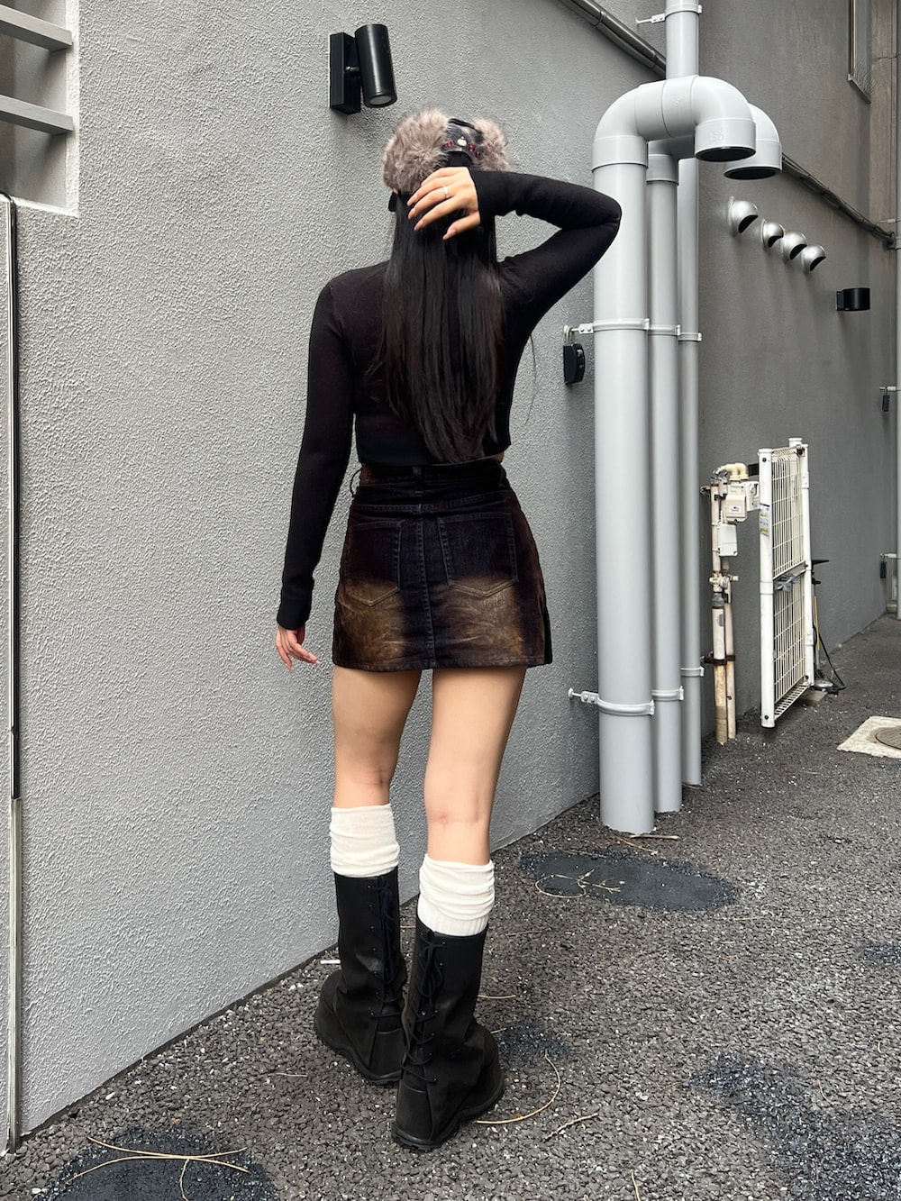 ブラック系のニット/セーター、ブラウン系のスカート、ブラック系のブーツを着用したレディースの夏コーディネートの3枚目の写真
