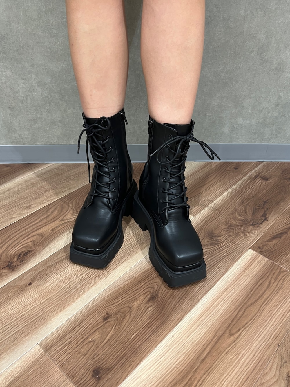 グレー系のワンピース、ブラック系のブルゾン、ブラック系のブーツを着用したレディースの冬コーディネートの6枚目の写真