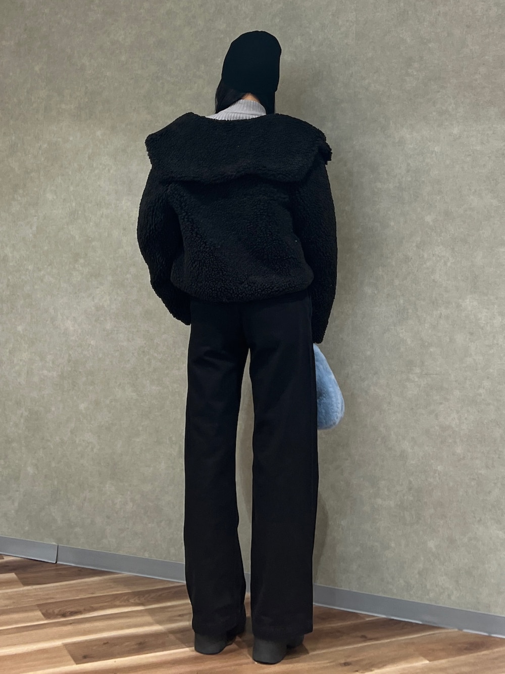 グレー系のニット/セーター、ブルー系のハンドバッグ、ブラック系のブルゾンを着用したレディースの冬コーディネートの3枚目の写真