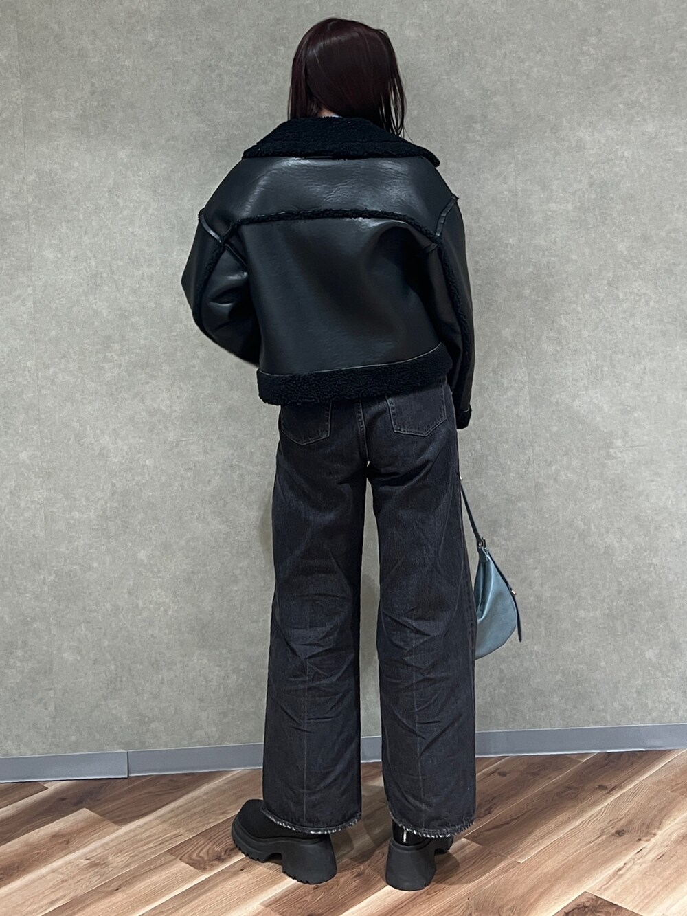 ブラック系のブルゾン、ブルー系のニット/セーター、ブラック系のデニムパンツを着用したレディースの冬コーディネートの3枚目の写真