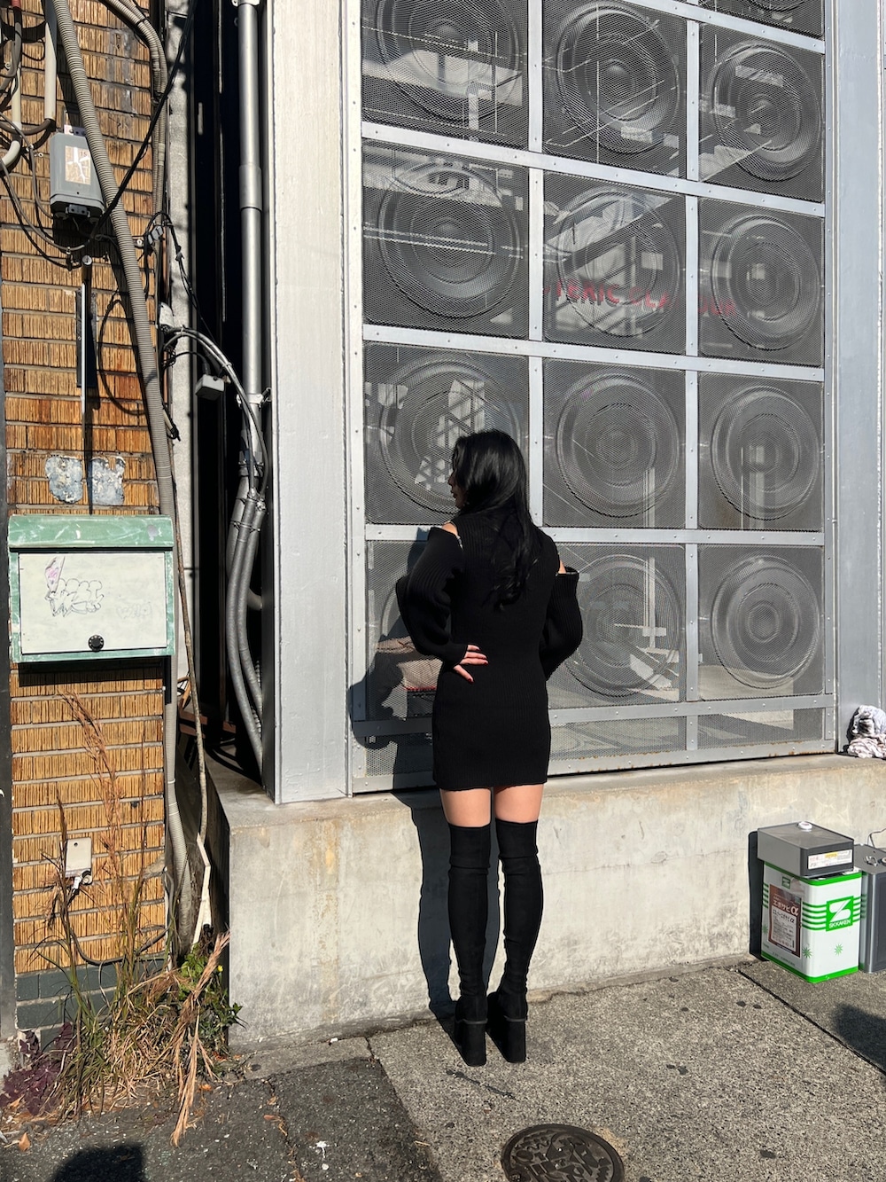 ブラック系のワンピース、ホワイト系のハンドバッグ、ブラック系のブーツを着用したレディースの冬コーディネートの2枚目の写真