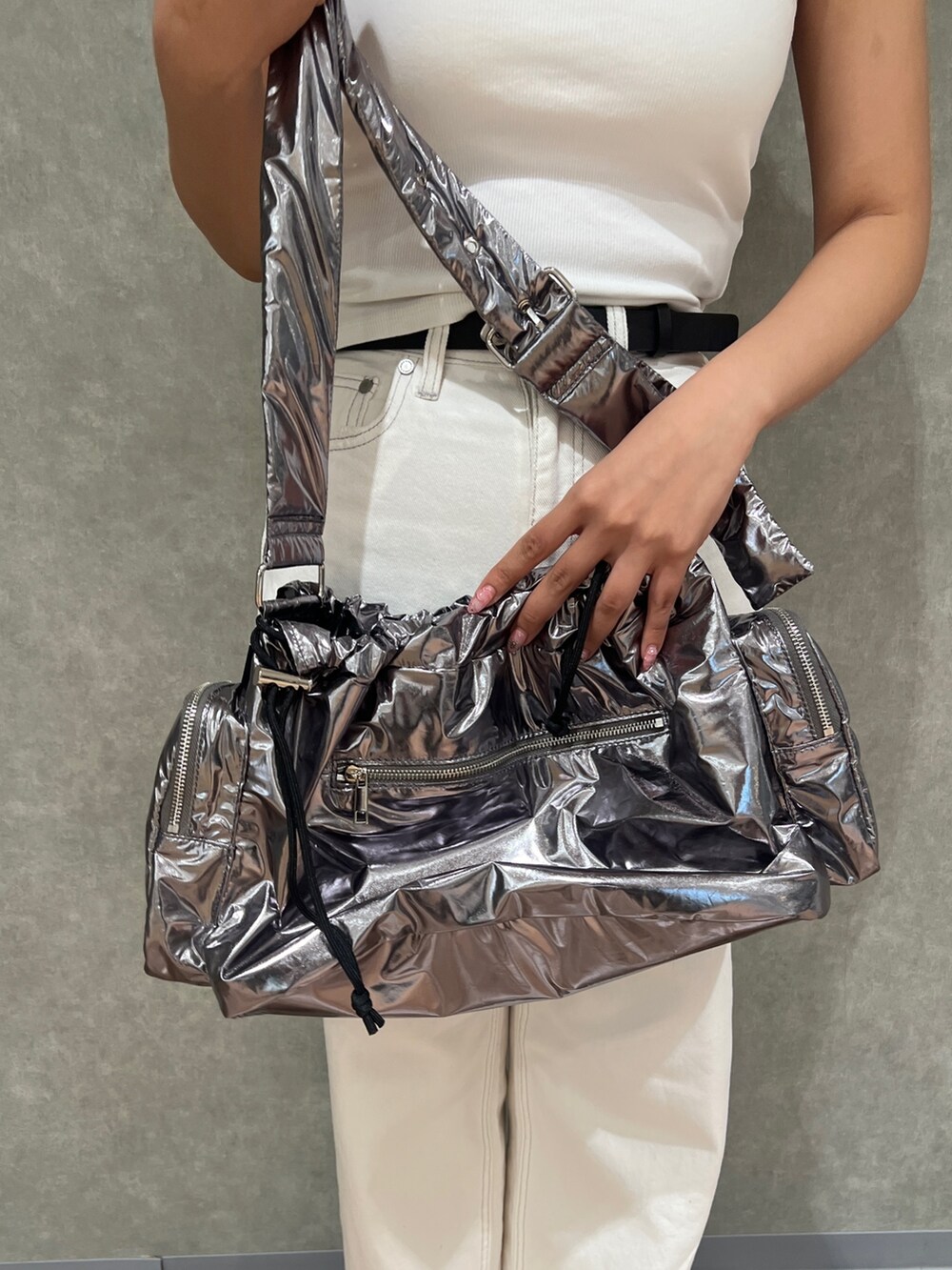 ホワイト系のタンクトップ、ホワイト系のデニムパンツ、シルバー系のハンドバッグを着用したレディースの夏コーディネートの6枚目の写真