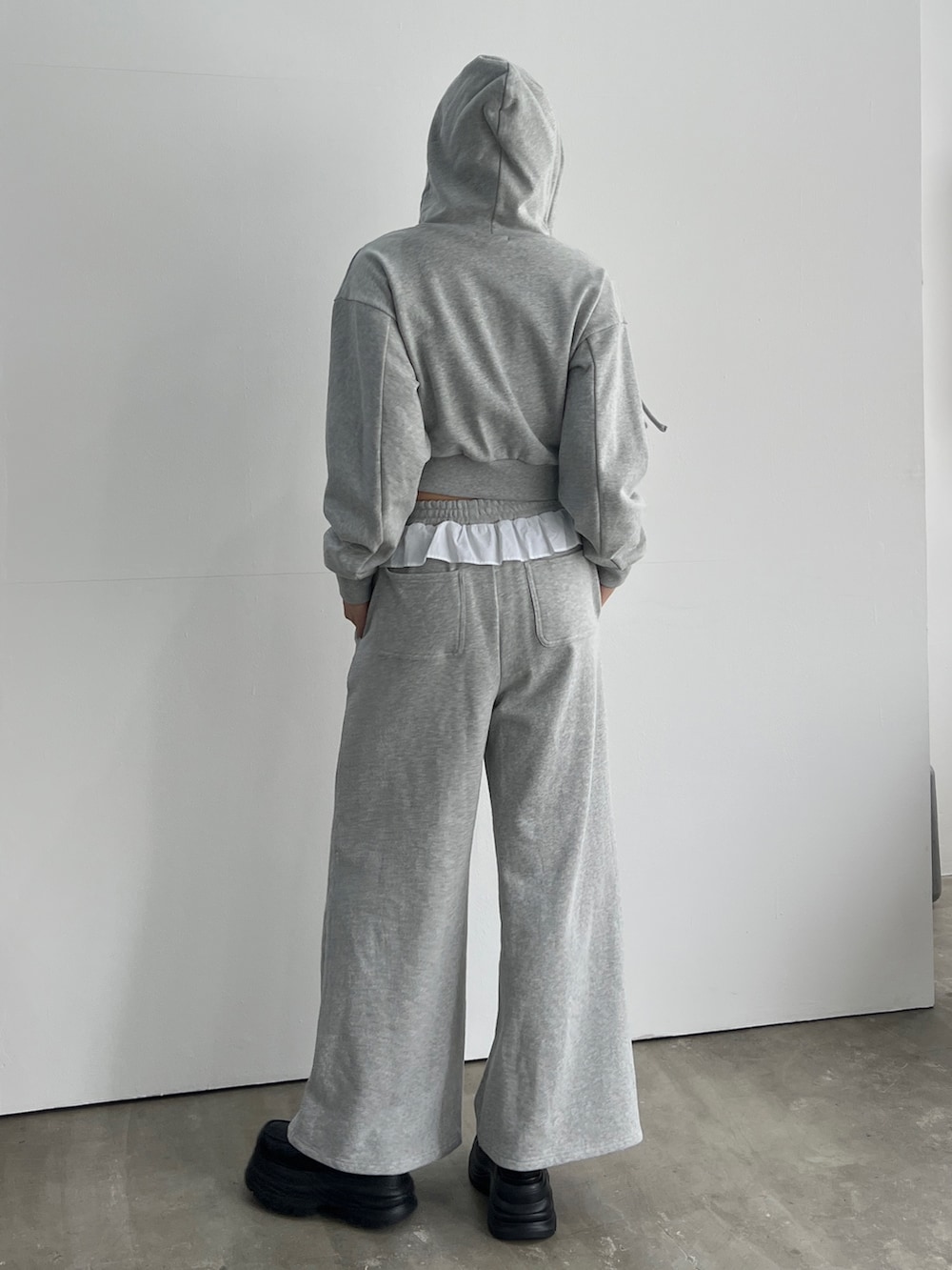 グレー系のパーカー、グレー系のスウェットパンツ、ブラック系のローファーを着用したレディースの冬コーディネートの2枚目の写真