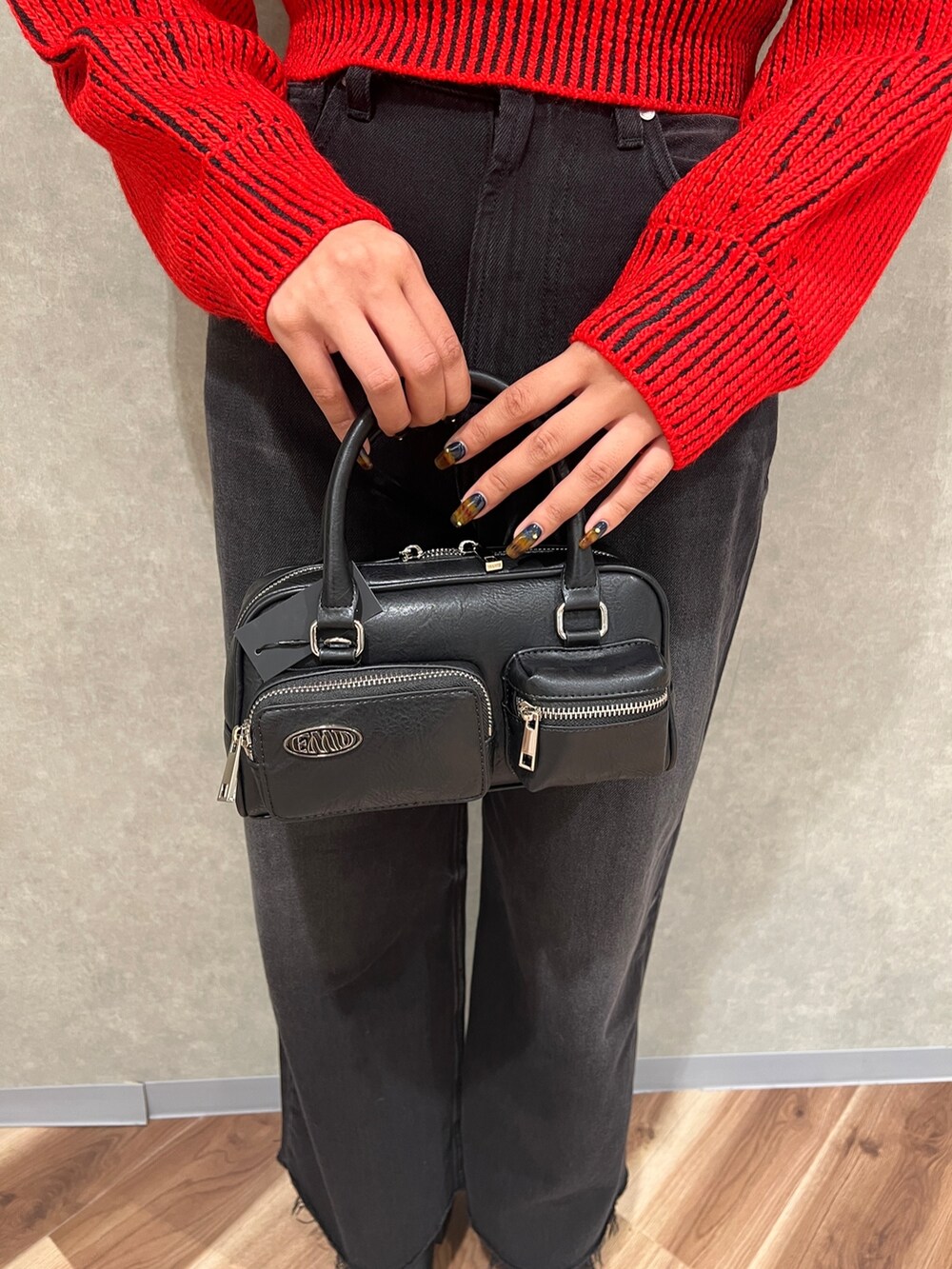 レッド系のニット/セーター、ブラック系のデニムパンツ、ブラック系のブーツを着用したレディースの秋コーディネートの9枚目の写真