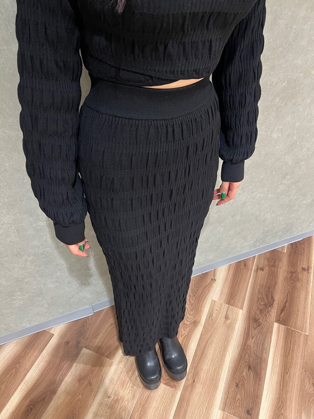 ブラック系のニット/セーター、ブラック系のスカート、ブラック系のブーツを着用したレディースの冬コーディネートの4枚目の写真