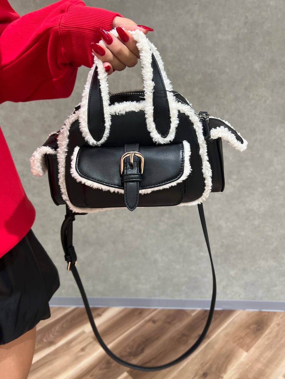 レッド系のスウェット、ブラック系のハンドバッグ、ブラック系のブーツを着用したレディースの秋コーディネートの7枚目の写真