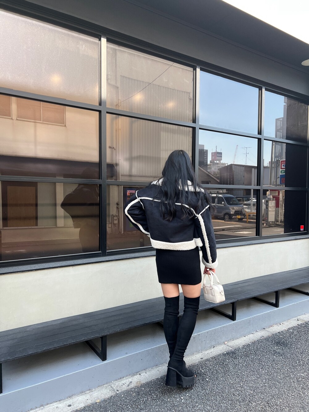 ブラック系のワンピース、ブラック系のブーツ、その他のブルゾンを着用したレディースの冬コーディネートの2枚目の写真