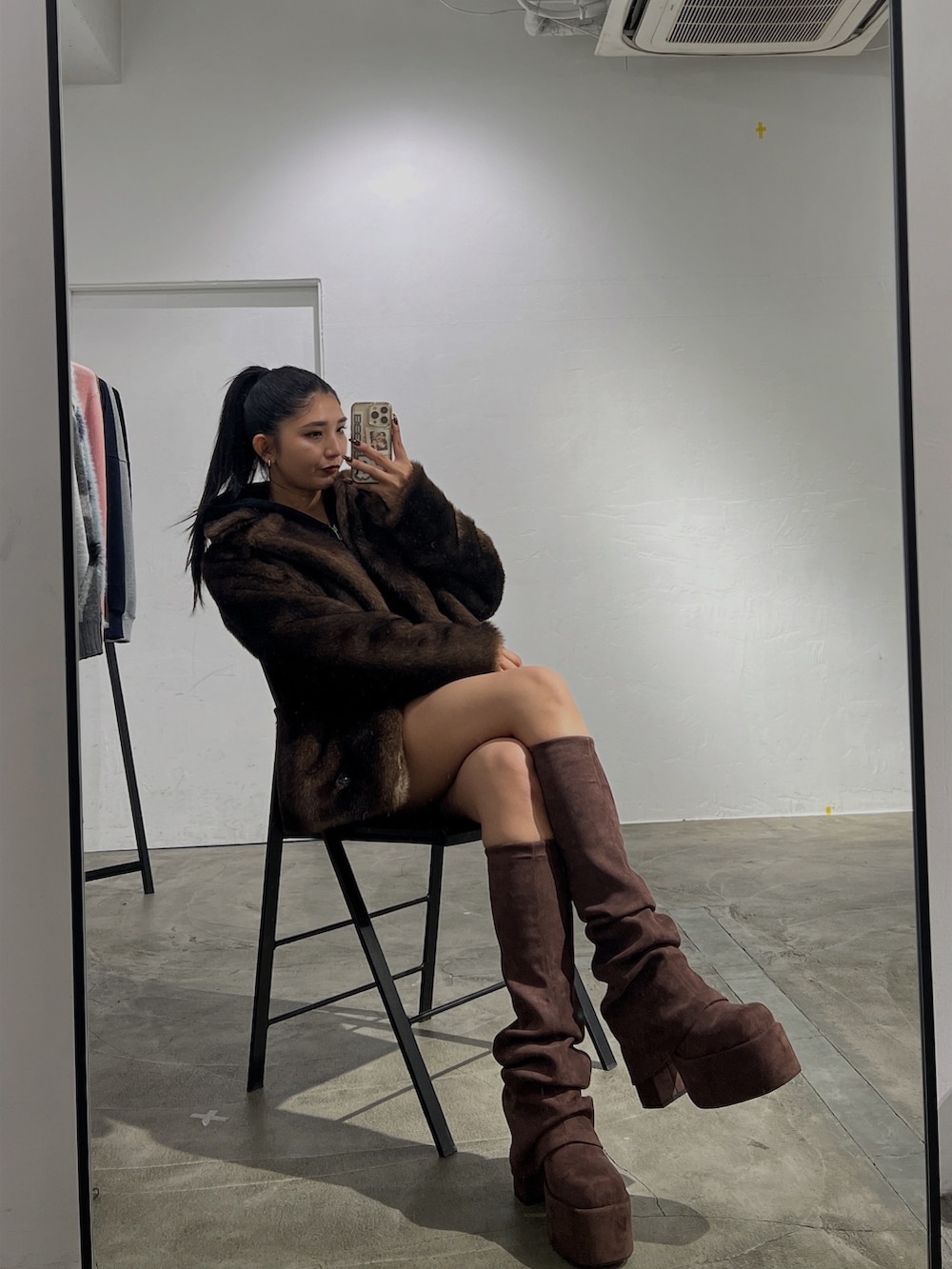 ブラック系のパーカー、ブラウン系のスカート、ブラウン系のブーツを着用したレディースの秋コーディネートの2枚目の写真