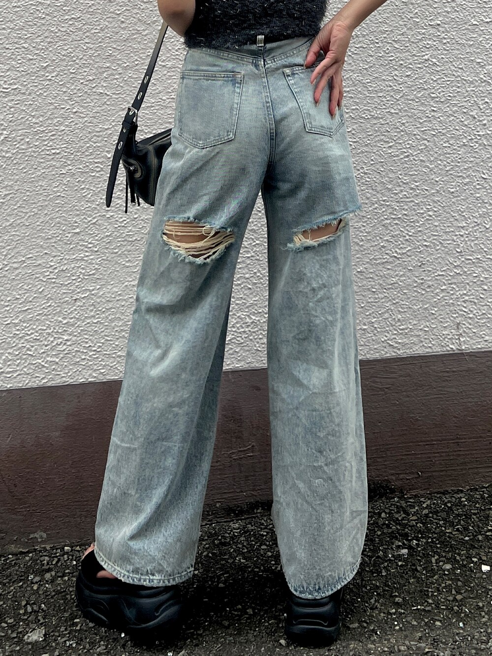 グレー系のタンクトップ、ブルー系のデニムパンツ、ブラック系のハンドバッグを着用したレディースの夏コーディネートの4枚目の写真