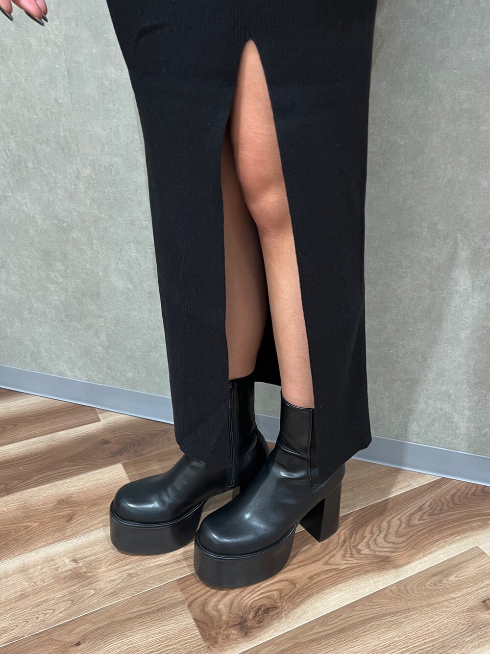 ブラック系のニット/セーター、ブラック系のスカート、ブラック系のブーツを着用したレディースの秋コーディネートの9枚目の写真