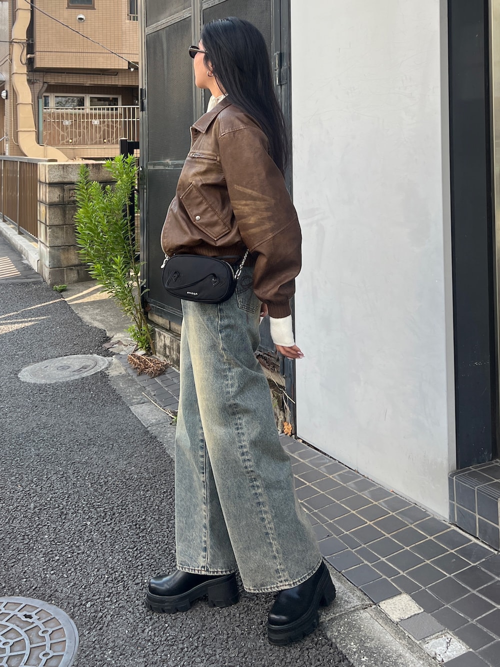 ブラウン系のブルゾン、ホワイト系のニット/セーター、ブルー系のデニムパンツを着用したレディースの秋コーディネートの2枚目の写真