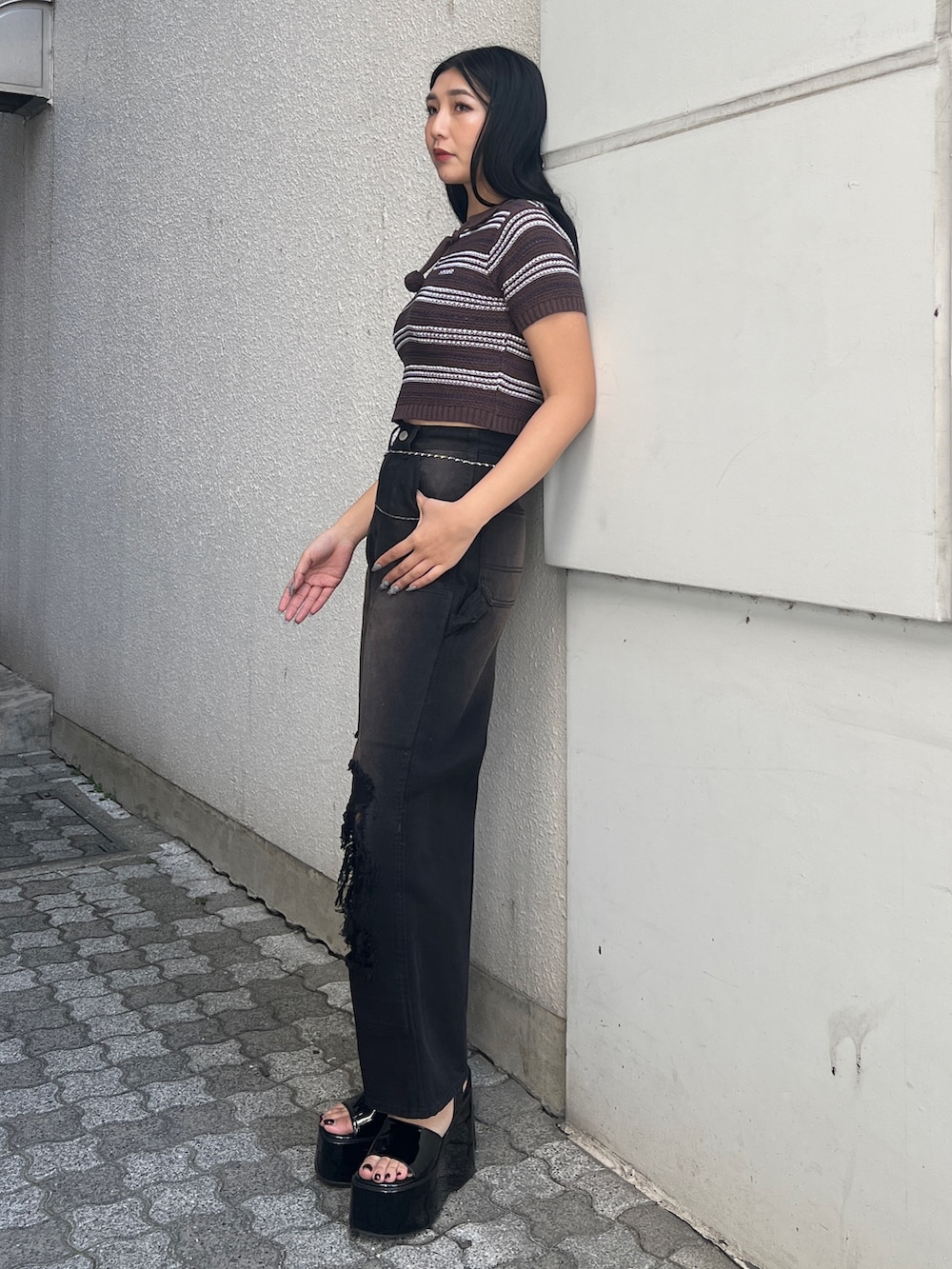 ブラウン系のニット/セーター、ブラック系のデニムパンツ、ブラック系のサンダルを着用したレディースの春コーディネートの2枚目の写真