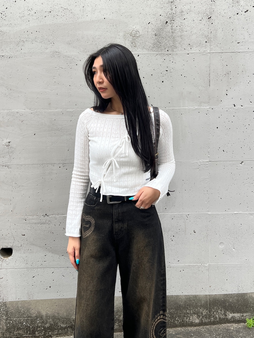 ホワイト系のニット/セーター、ブラック系のデニムパンツを着用したレディースの春コーディネートの3枚目の写真