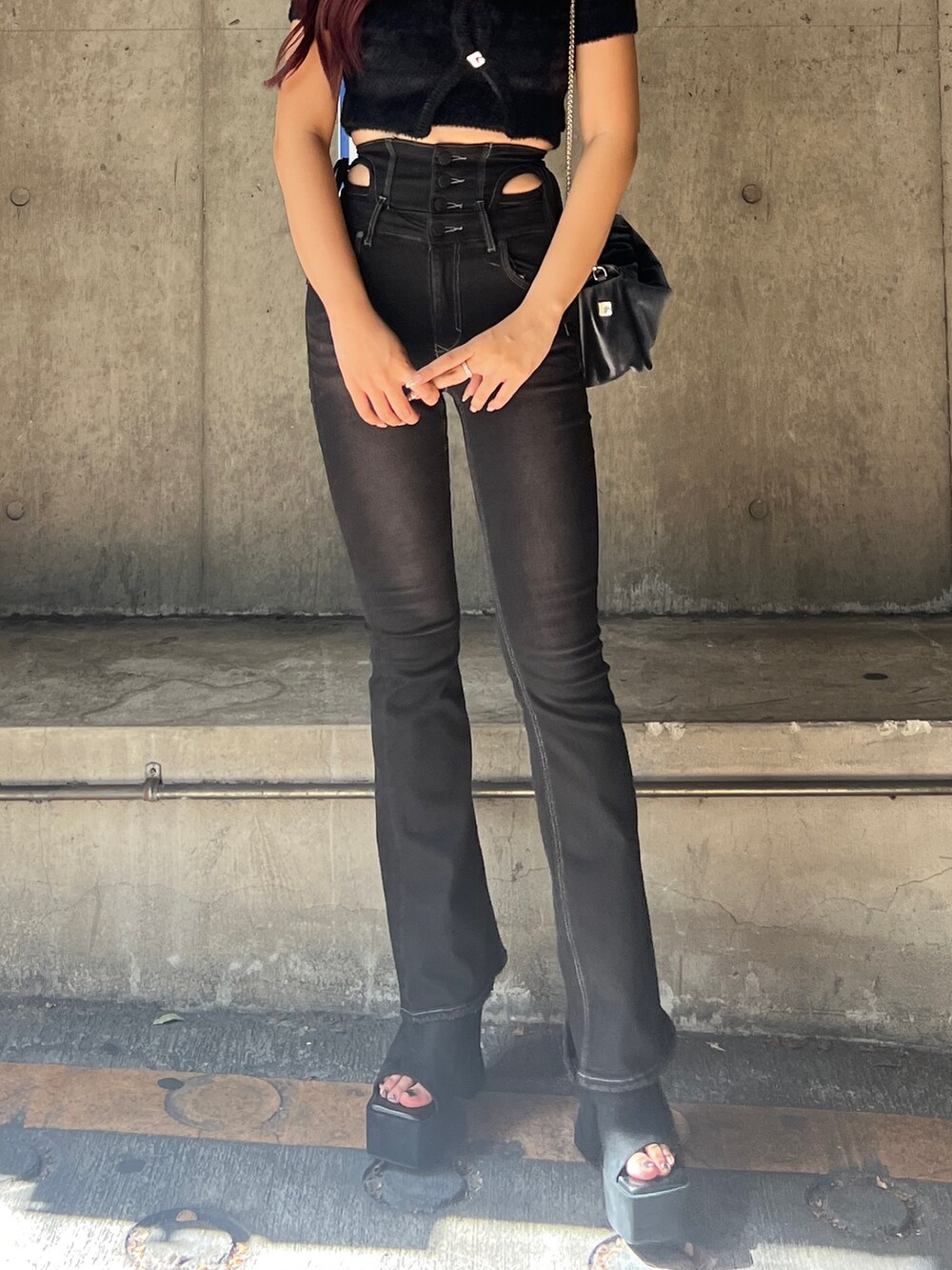 ブラック系のニット/セーター、ブラック系のデニムパンツ、グレー系のハンドバッグを着用したレディースの夏コーディネートの5枚目の写真