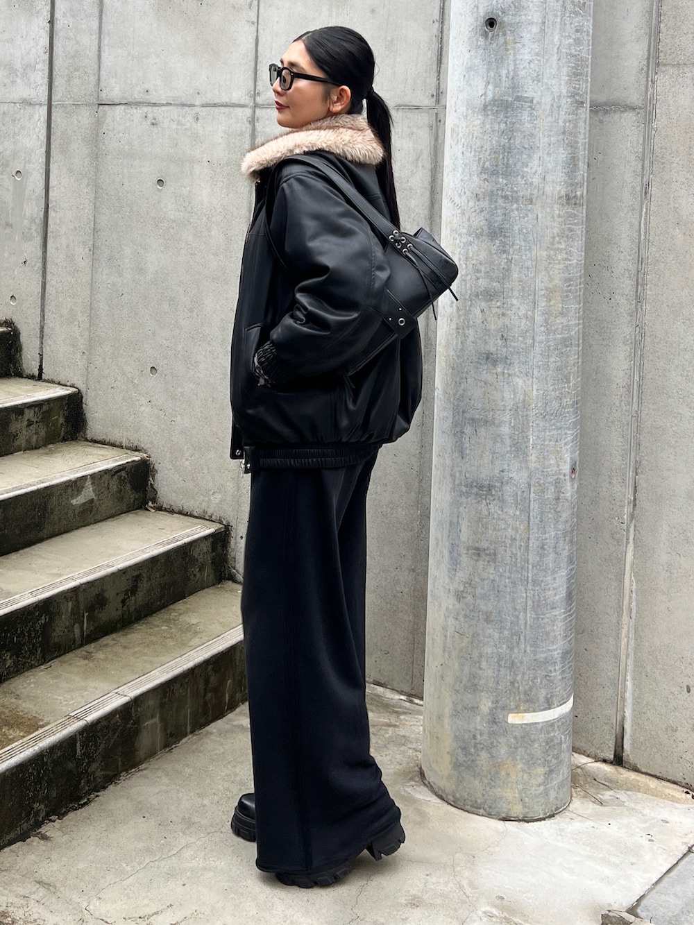 ブラック系のブルゾン、ブラック系のスウェットパンツ、ブラック系のブーツを着用したレディースの秋コーディネートの2枚目の写真