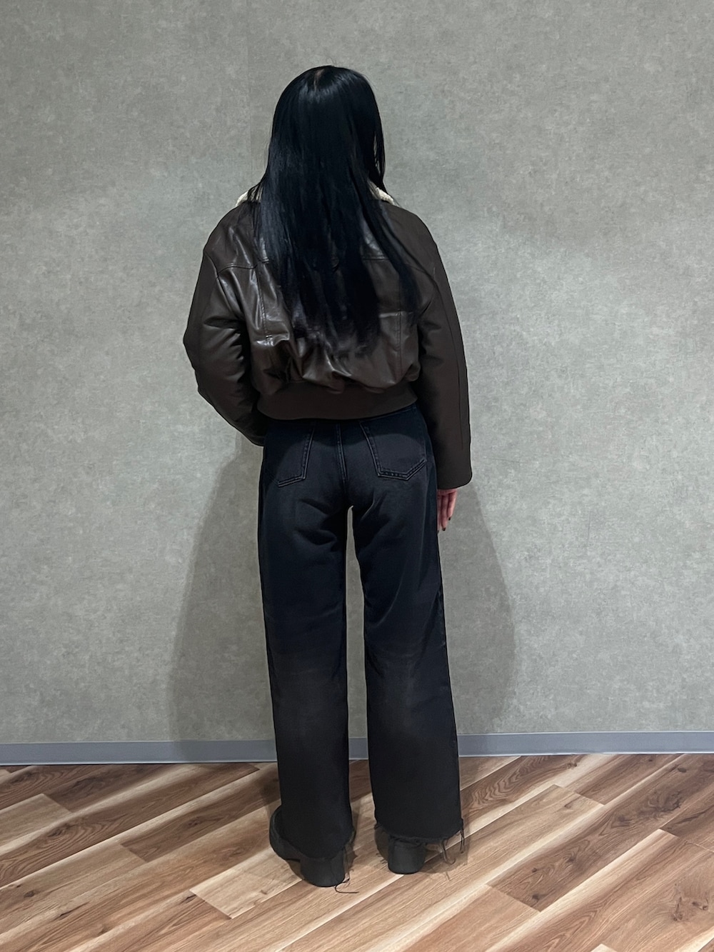 ブラウン系のブルゾン、ブラック系のニット/セーター、ブラック系のデニムパンツを着用したレディースの秋コーディネートの3枚目の写真