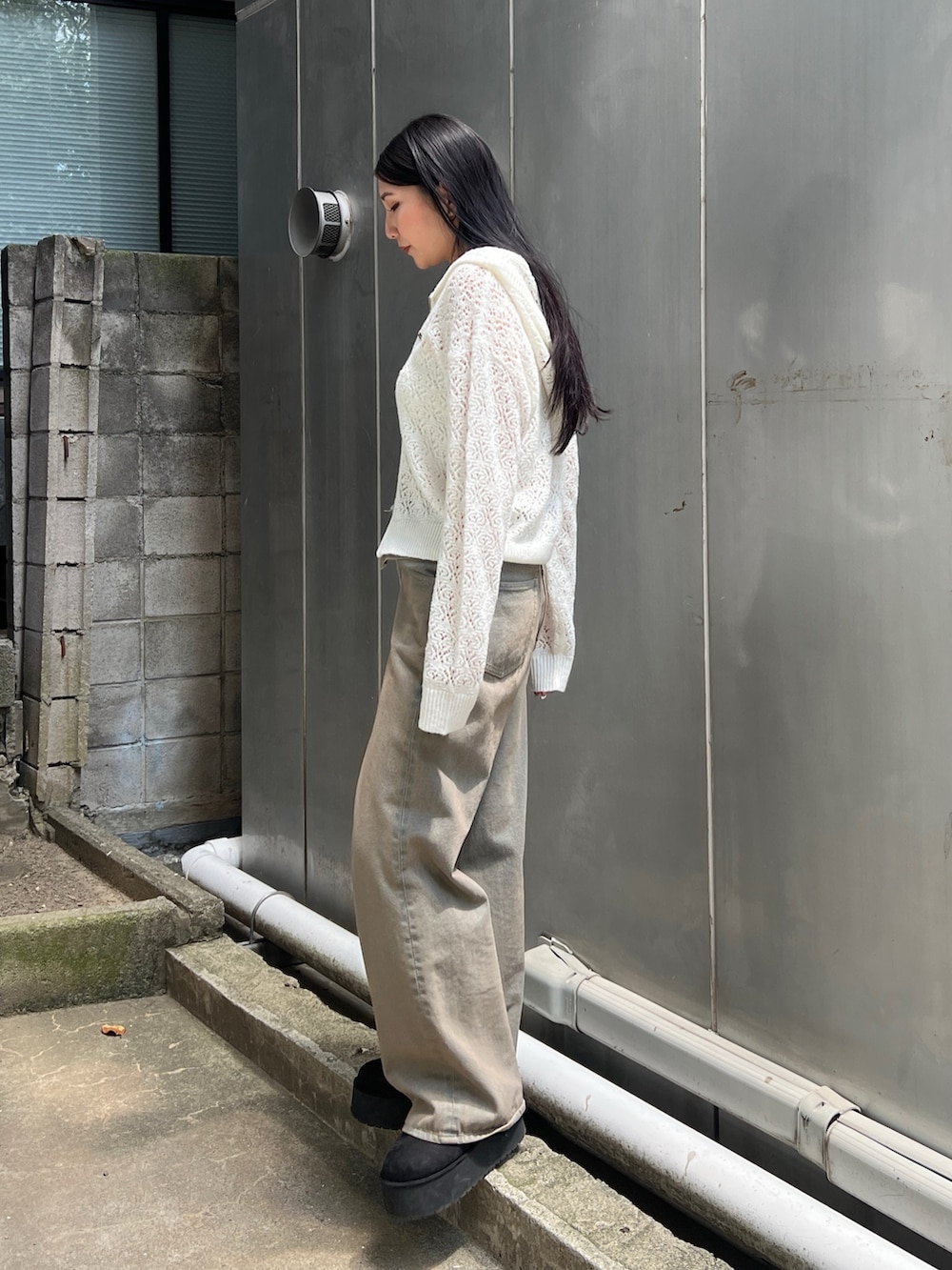 ホワイト系のニット/セーター、ホワイト系のキャミソール、ブラウン系のデニムパンツを着用したレディースの夏コーディネートの2枚目の写真