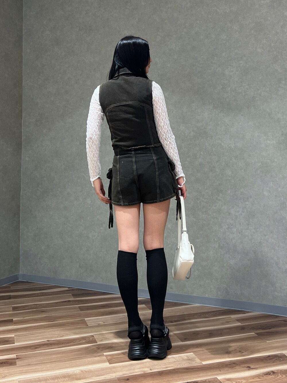 ブラック系のベスト、ブラック系のその他パンツ、ホワイト系のハンドバッグを着用したレディースの春コーディネートの3枚目の写真