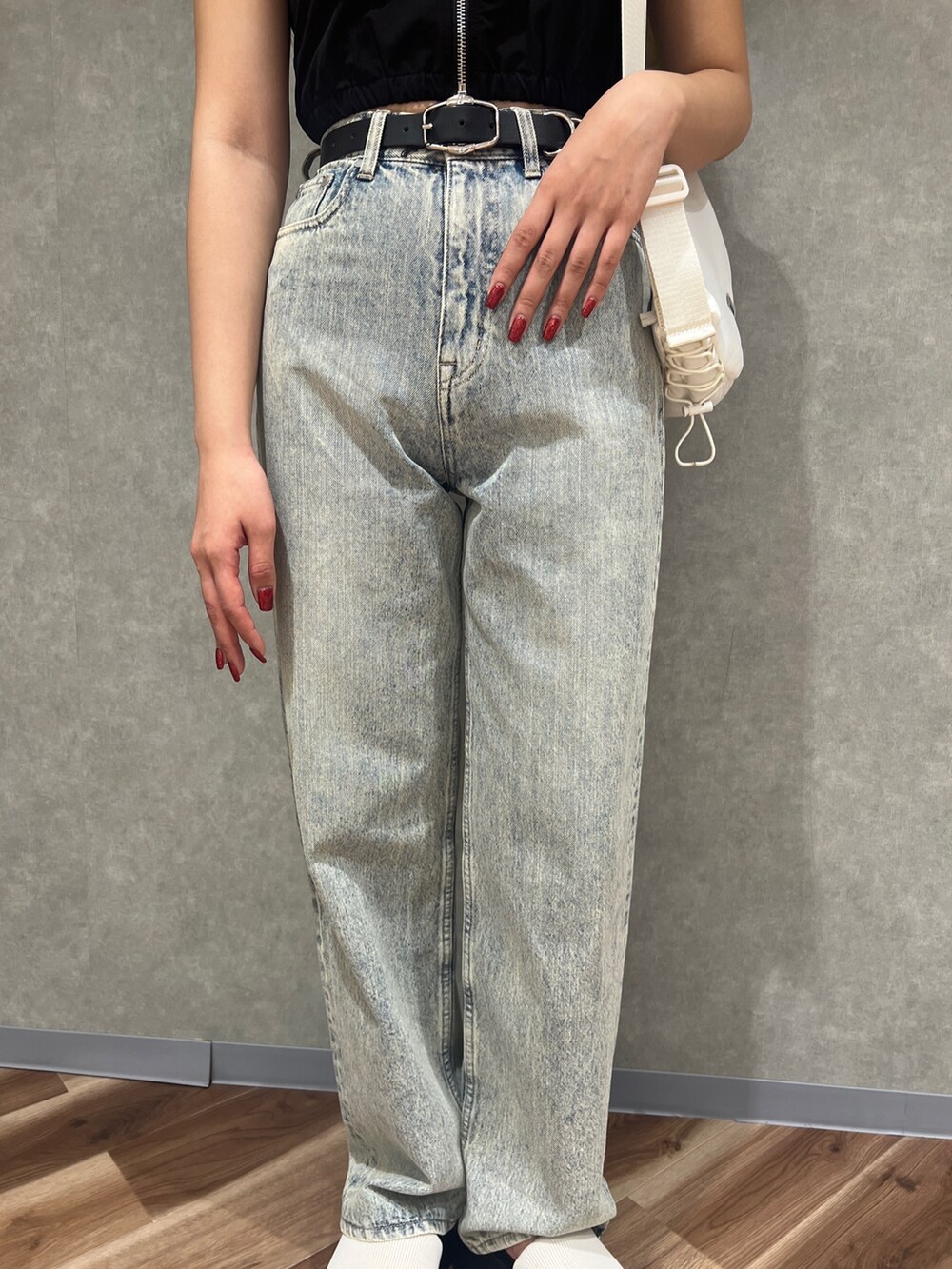 ブラック系のタンクトップ、ブルー系のデニムパンツ、ホワイト系のサンダルを着用したレディースの春コーディネートの5枚目の写真