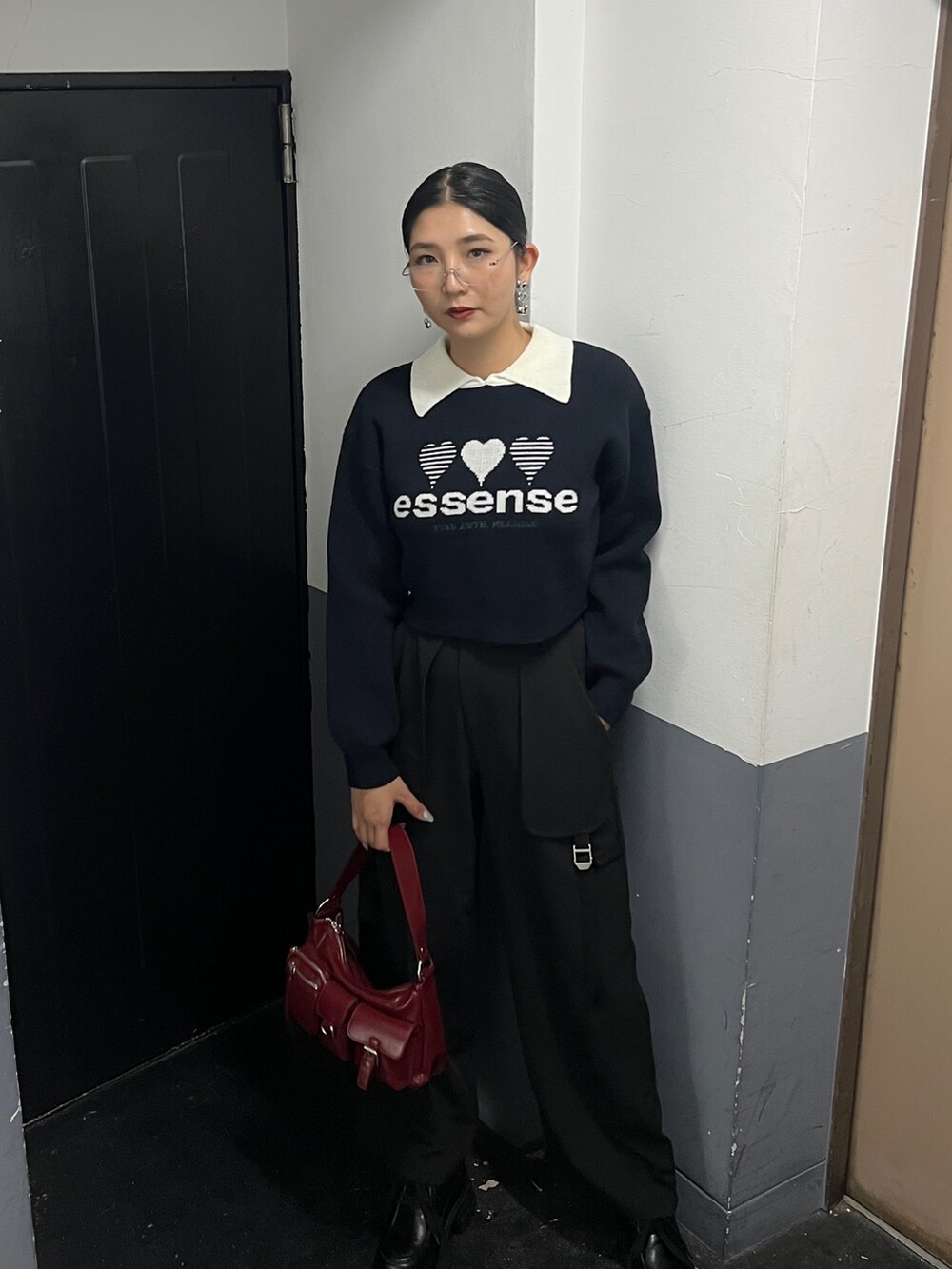 ブラック系のニット/セーター、ブラック系のその他パンツ、レッド系のハンドバッグを着用したレディースの秋コーディネートの4枚目の写真