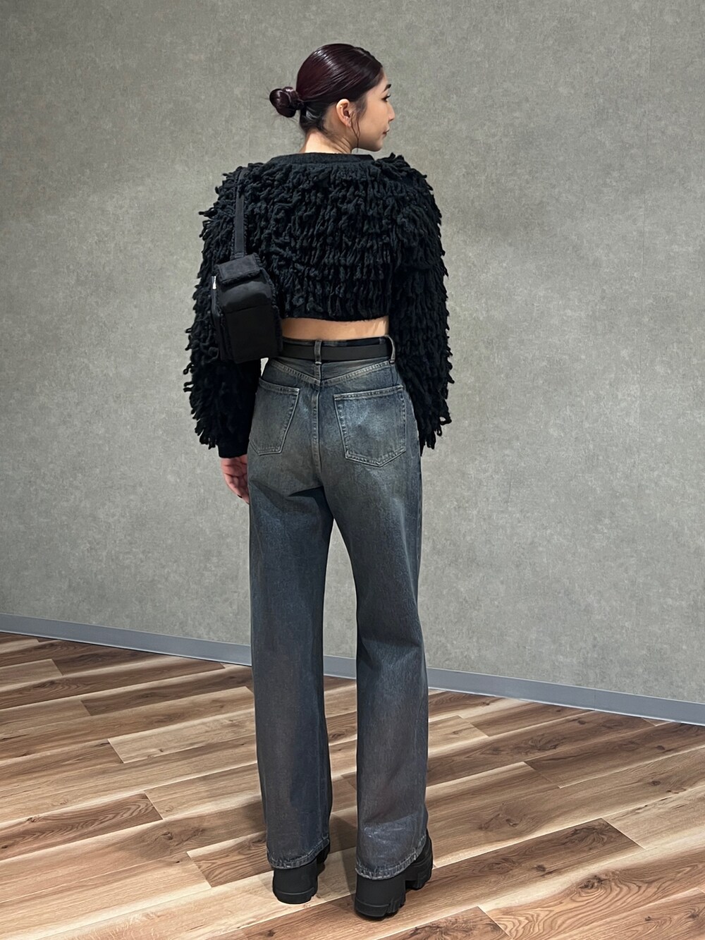 ブラック系のニット/セーター、ブルー系のデニムパンツ、ブラック系のブーツを着用したレディースの冬コーディネートの4枚目の写真