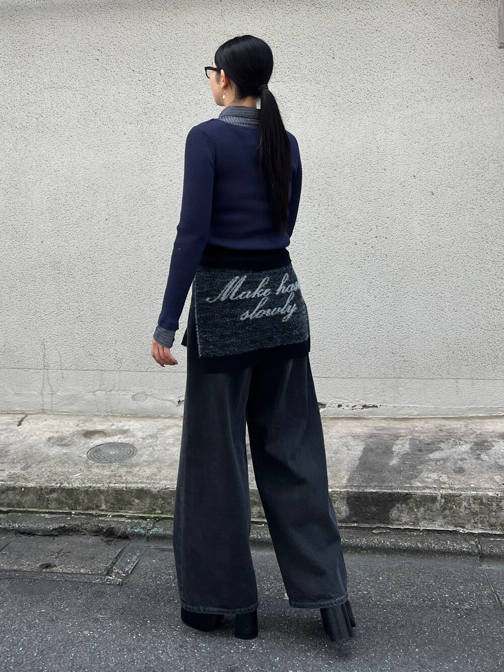 ブルー系のニット/セーター、ブラック系のブーツ、ブラック系のデニムパンツを着用したレディースの夏コーディネートの3枚目の写真