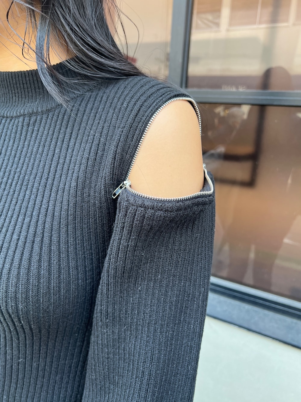 ブラック系のワンピース、ホワイト系のハンドバッグ、ブラック系のブーツを着用したレディースの冬コーディネートの3枚目の写真