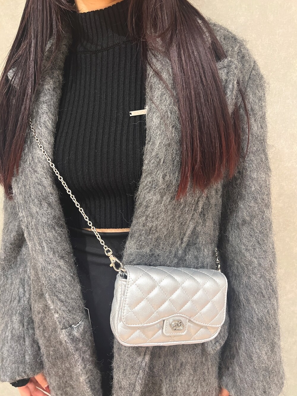 グレー系のチェスターコート、ブラック系のブーツ、ブラック系のニット/セーターを着用したレディースの冬コーディネートの5枚目の写真