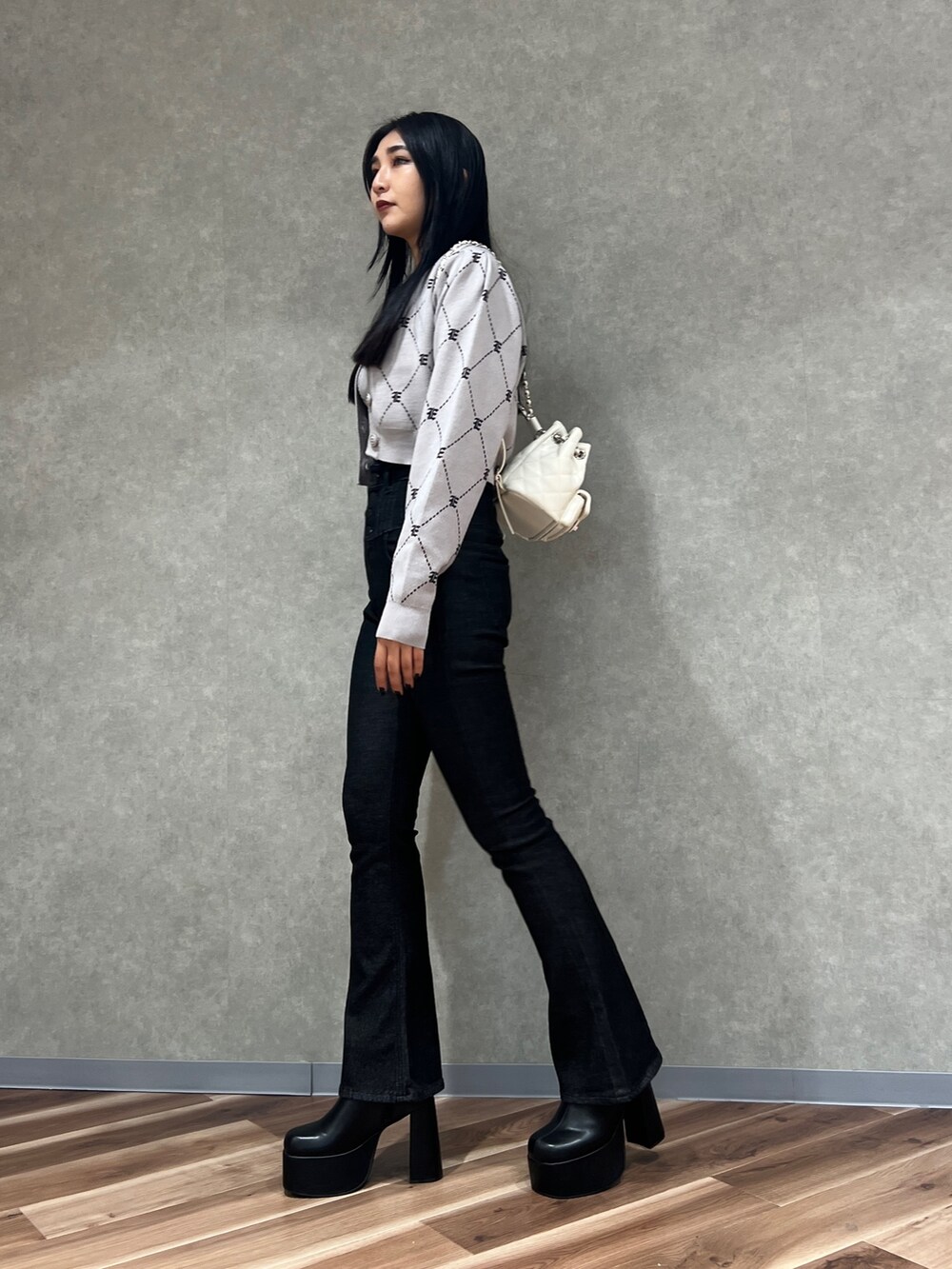 ブラック系のデニムパンツ、ブラック系のブーツ、グレー系のニット/セーターを着用したレディースの秋コーディネートの2枚目の写真