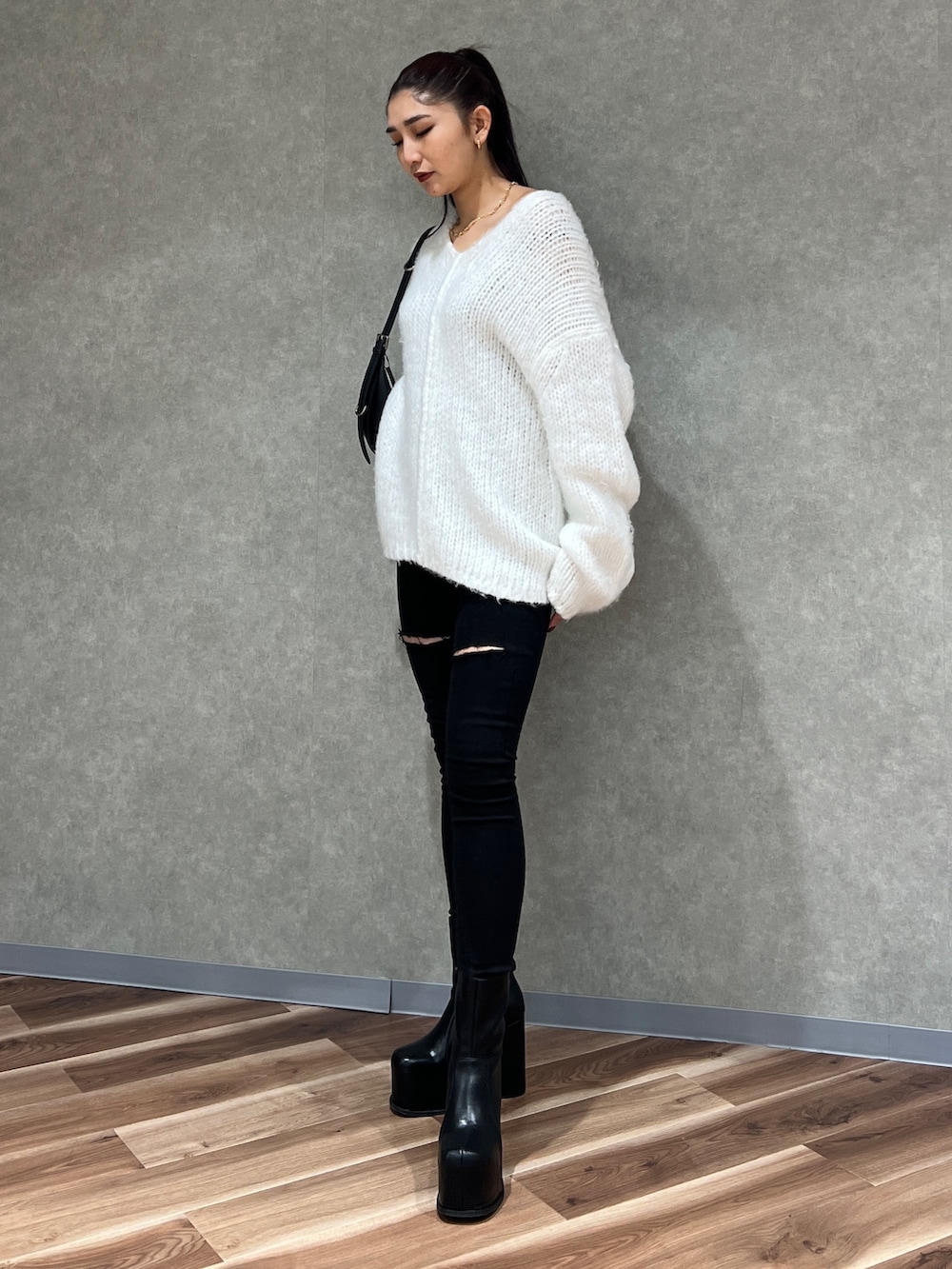 ホワイト系のニット/セーター、ブラック系のデニムパンツ、ブラック系のハンドバッグを着用したレディースの冬コーディネートの2枚目の写真