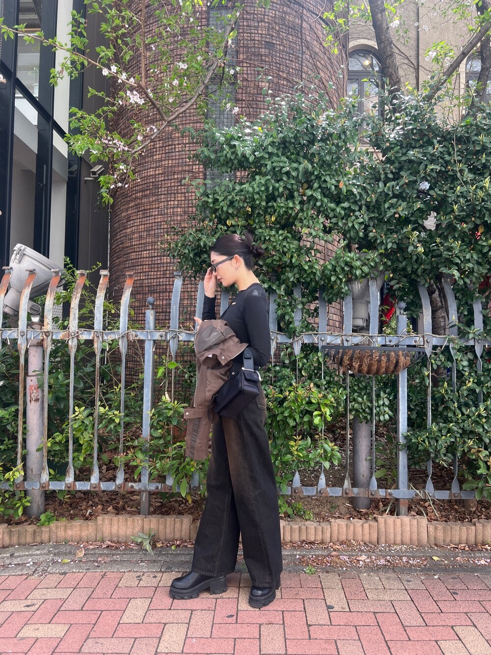 ブラック系のデニムパンツ、ブラック系のブーツ、ブラック系のTシャツ/カットソーを着用したレディースの春コーディネートの2枚目の写真