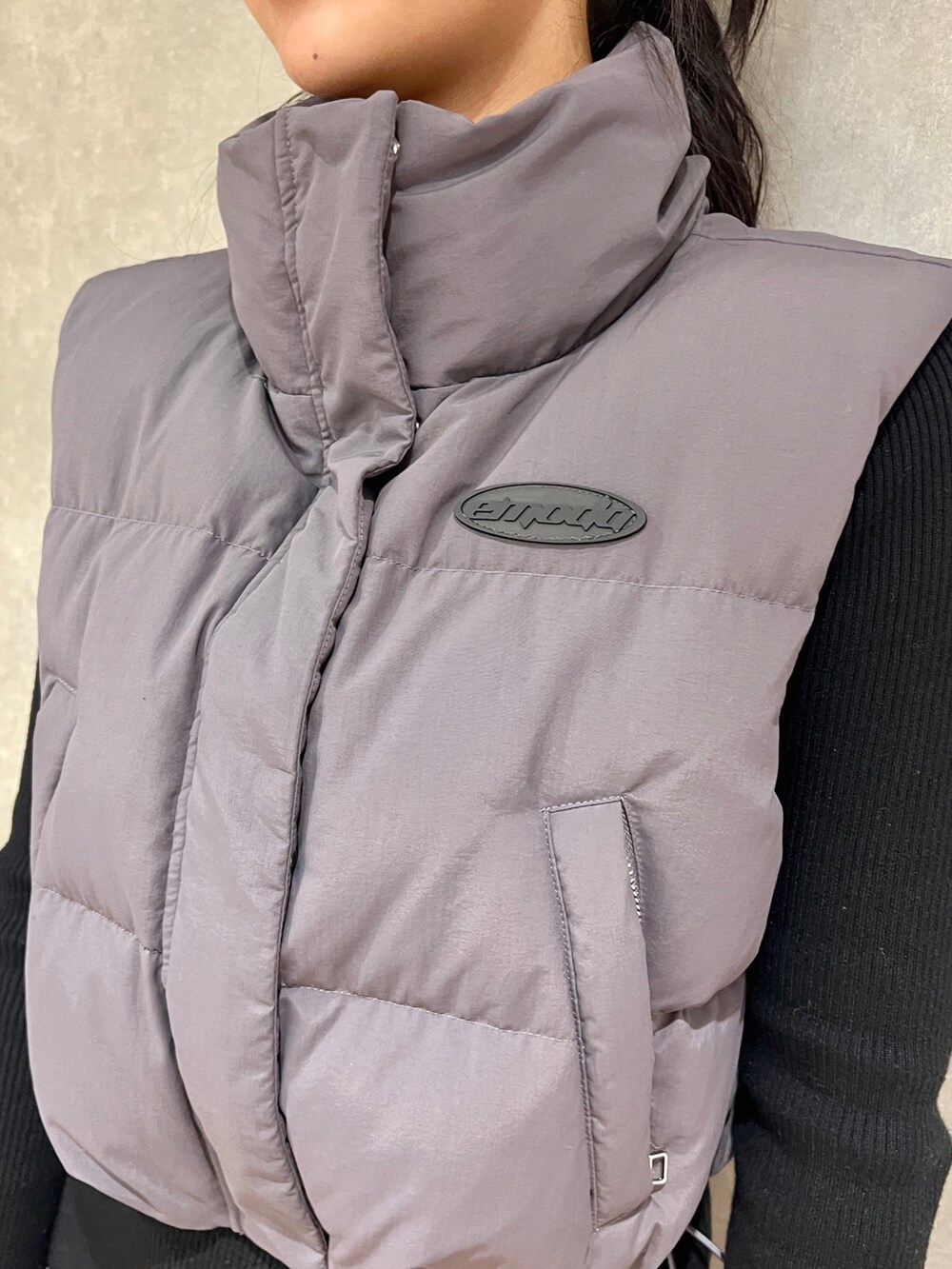 ブラック系のワンピース、グレー系のダウンベスト、ブラック系のブーツを着用したレディースの秋コーディネートの5枚目の写真