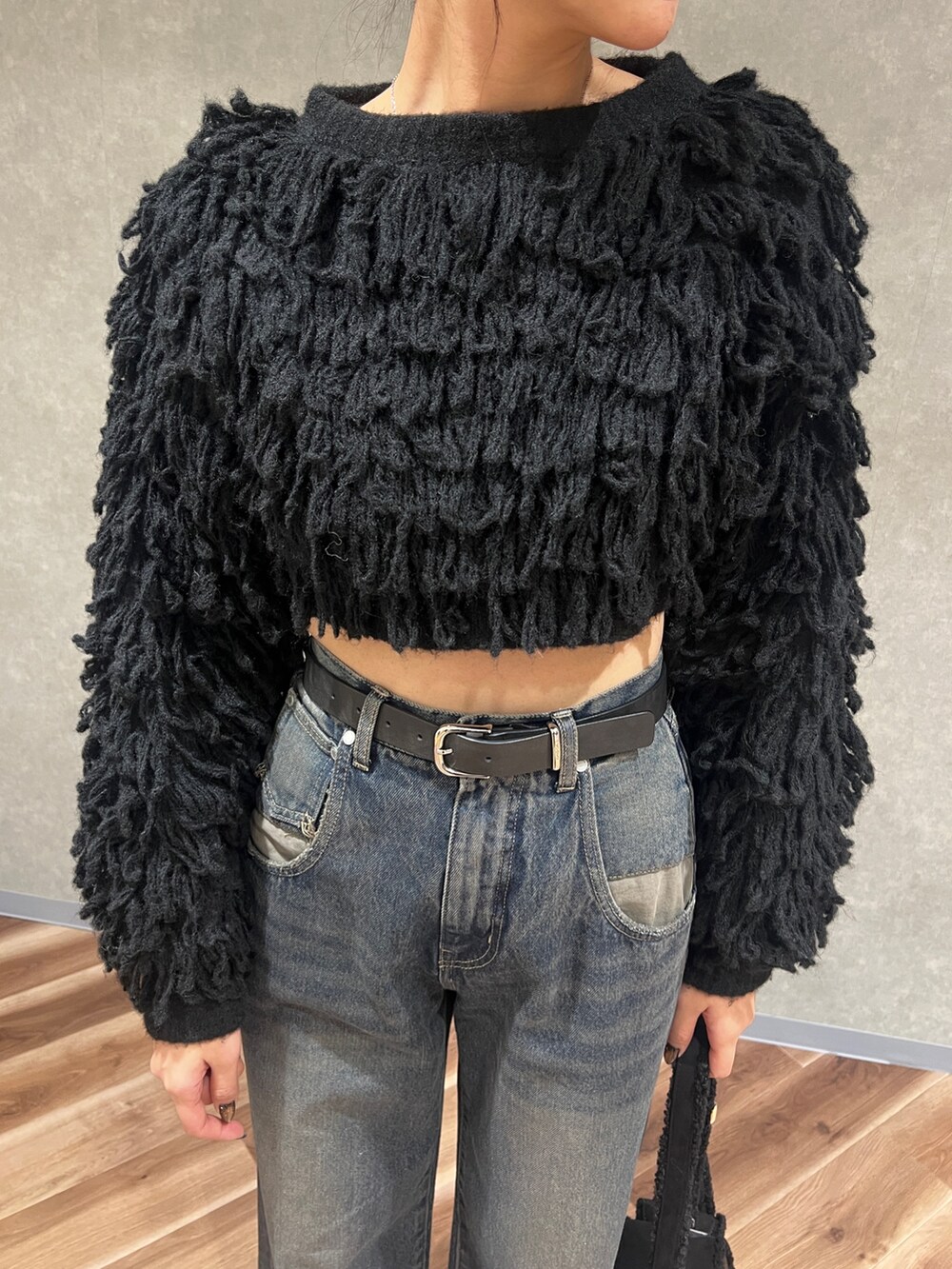 ブラック系のニット/セーター、ブルー系のデニムパンツ、ブラック系のブーツを着用したレディースの冬コーディネートの5枚目の写真