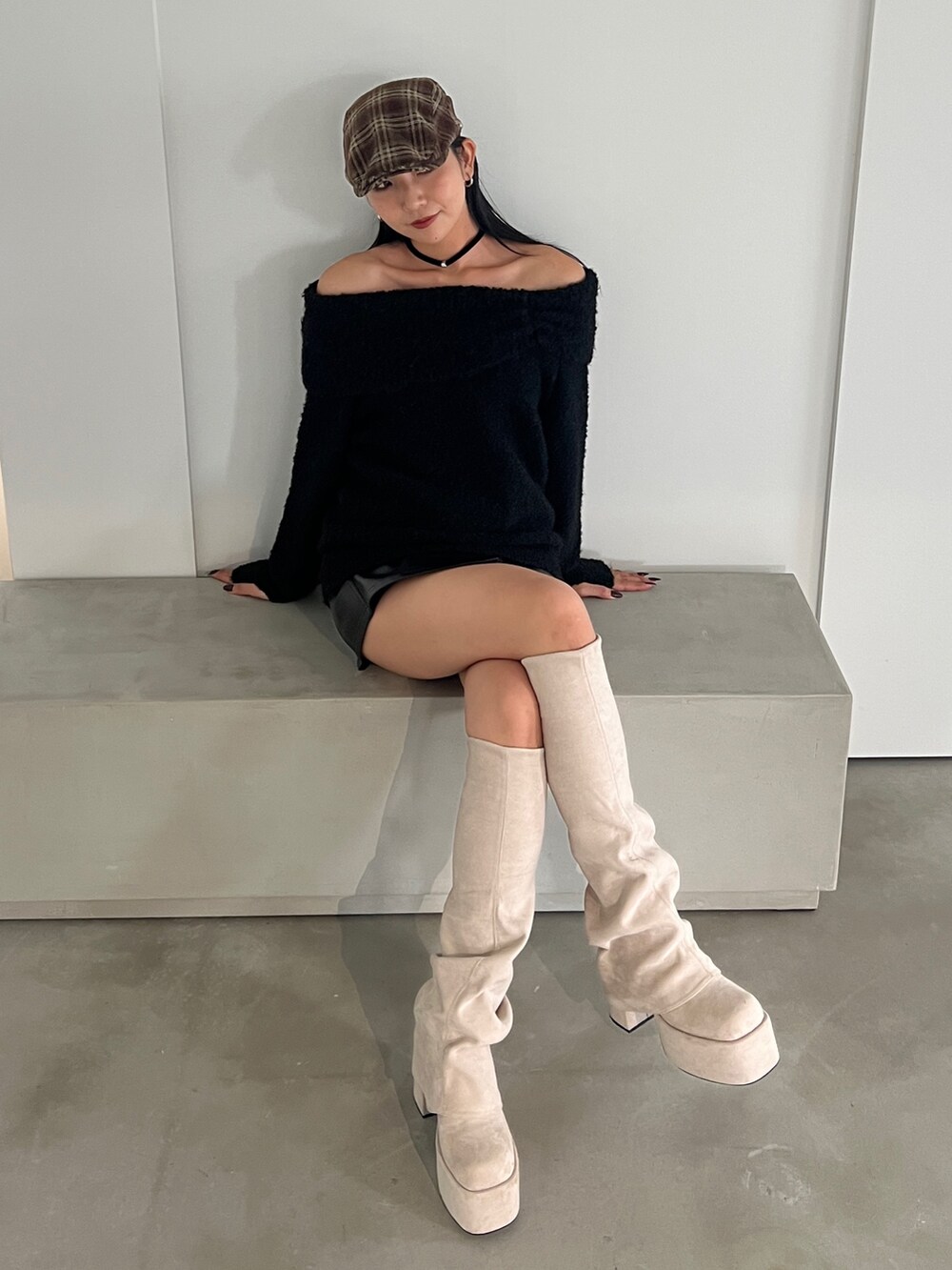 ブラック系のニット/セーター、ブラック系のスカート、ホワイト系のブーツを着用したレディースの秋コーディネートの3枚目の写真