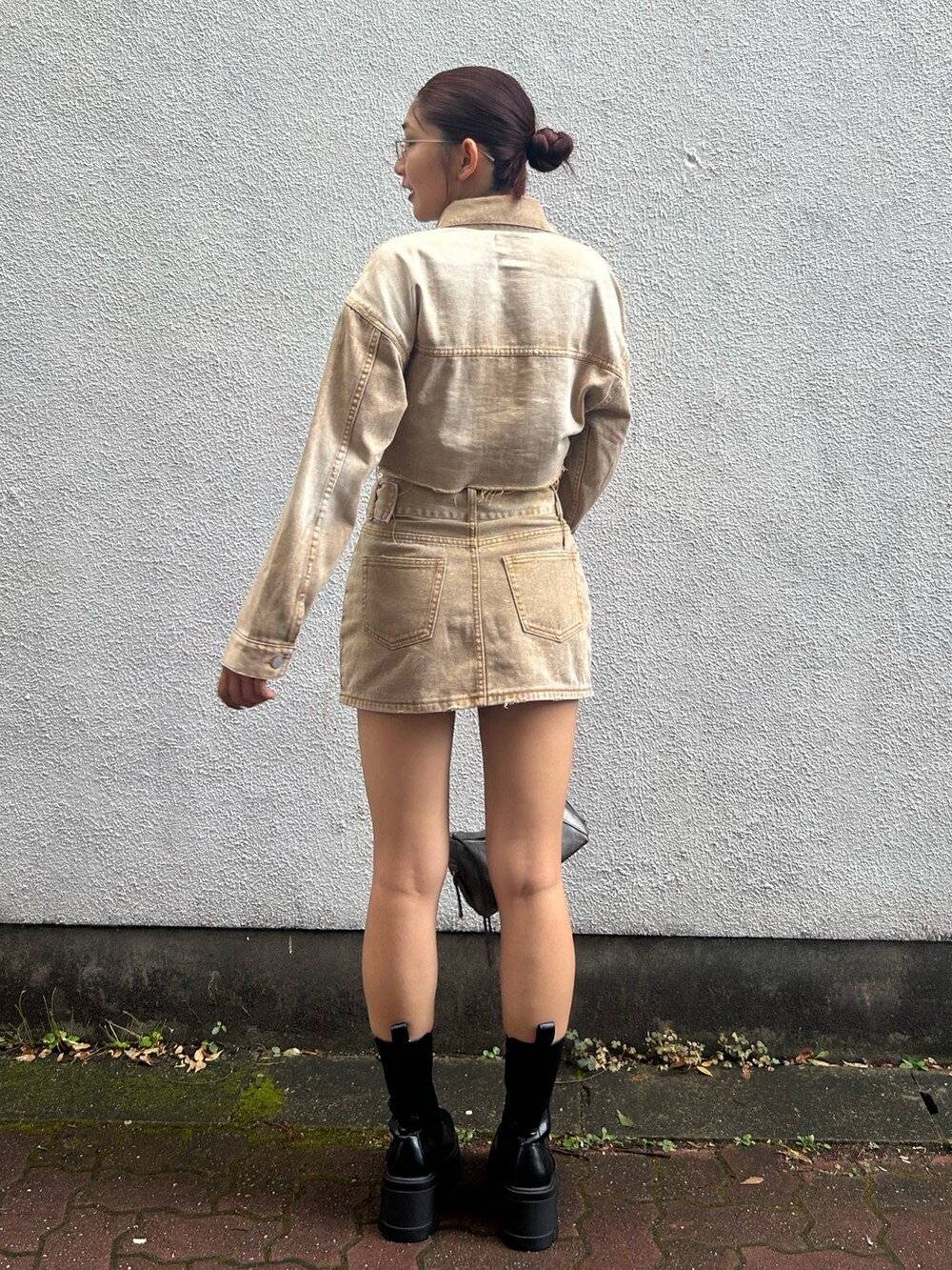 ベージュ系のデニムジャケット、ベージュ系のデニムスカート、シルバー系のハンドバッグを着用したレディースの夏コーディネートの3枚目の写真