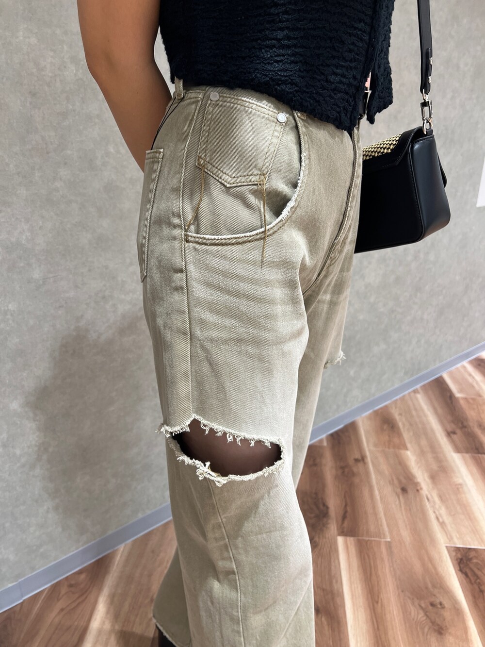 ブラック系のベスト、ホワイト系のニット/セーター、ベージュ系のデニムパンツを着用したレディースの夏コーディネートの6枚目の写真