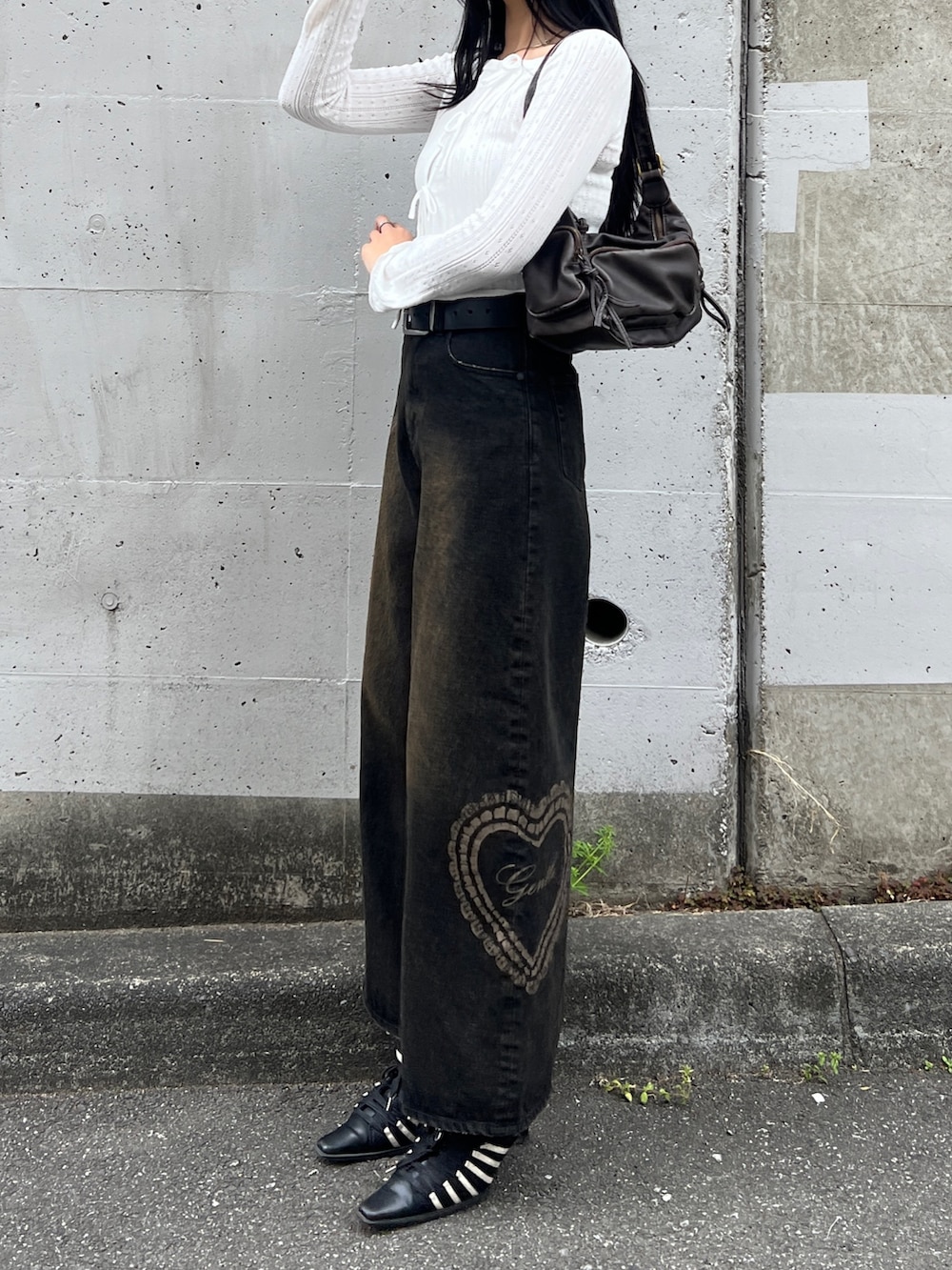 ホワイト系のニット/セーター、ブラック系のデニムパンツを着用したレディースの春コーディネートの2枚目の写真