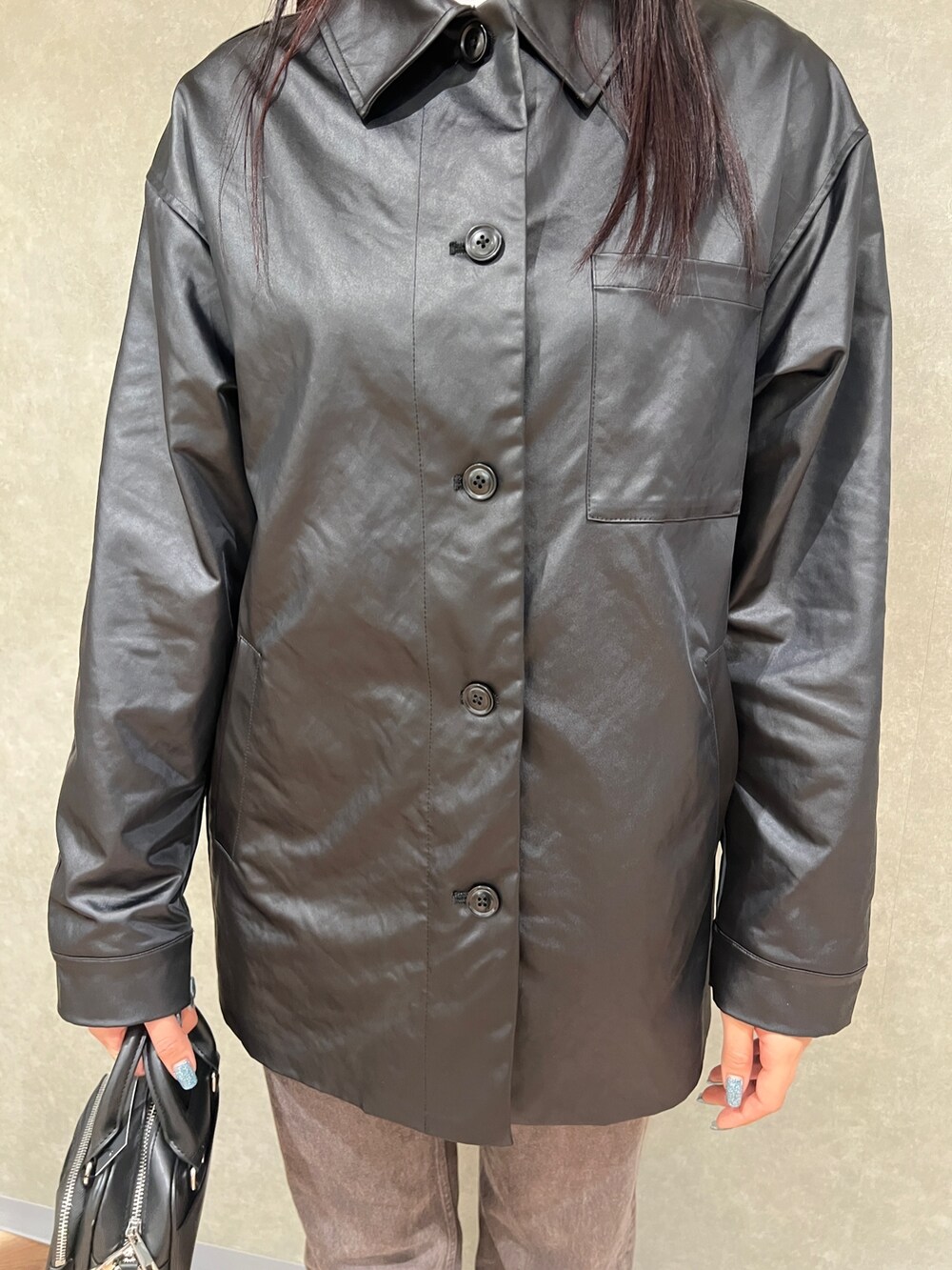 ブラック系のナイロンジャケット、ブラウン系のデニムパンツ、ブラック系のパンプスを着用したレディースの春コーディネートの4枚目の写真