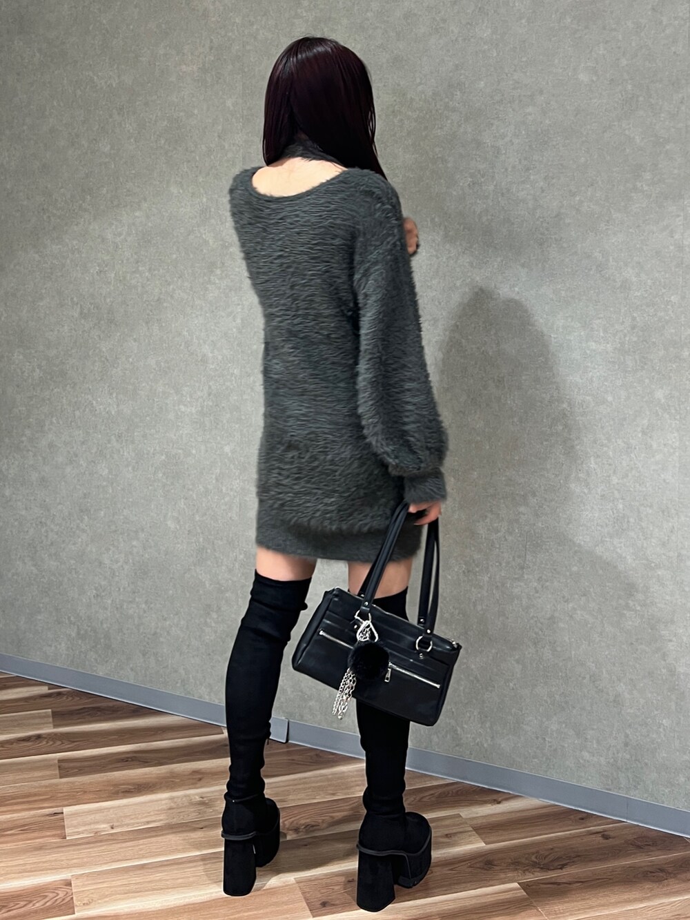 グレー系のワンピース、ブラック系のショルダーバッグ、ブラック系のブーツを着用したレディースの秋コーディネートの5枚目の写真