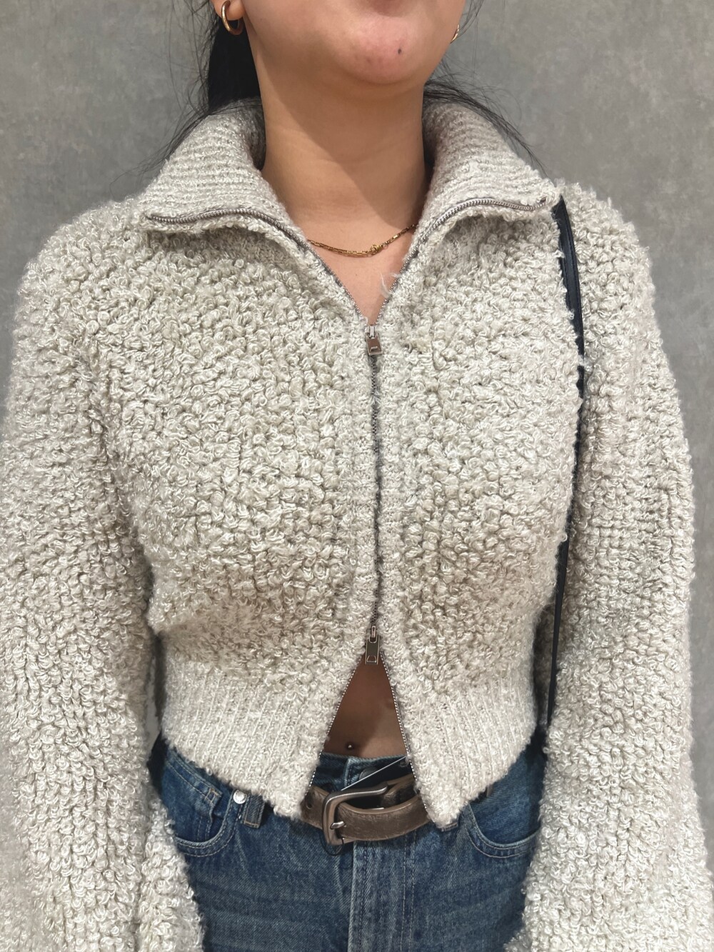 グレー系のニット/セーター、ブルー系のデニムパンツ、ホワイト系のブーツを着用したレディースの秋コーディネートの5枚目の写真