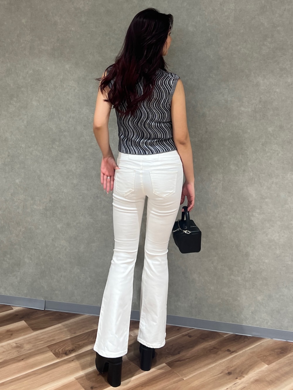 グレー系のタンクトップ、ホワイト系のデニムパンツ、ブラック系のハンドバッグを着用したレディースの夏コーディネートの4枚目の写真