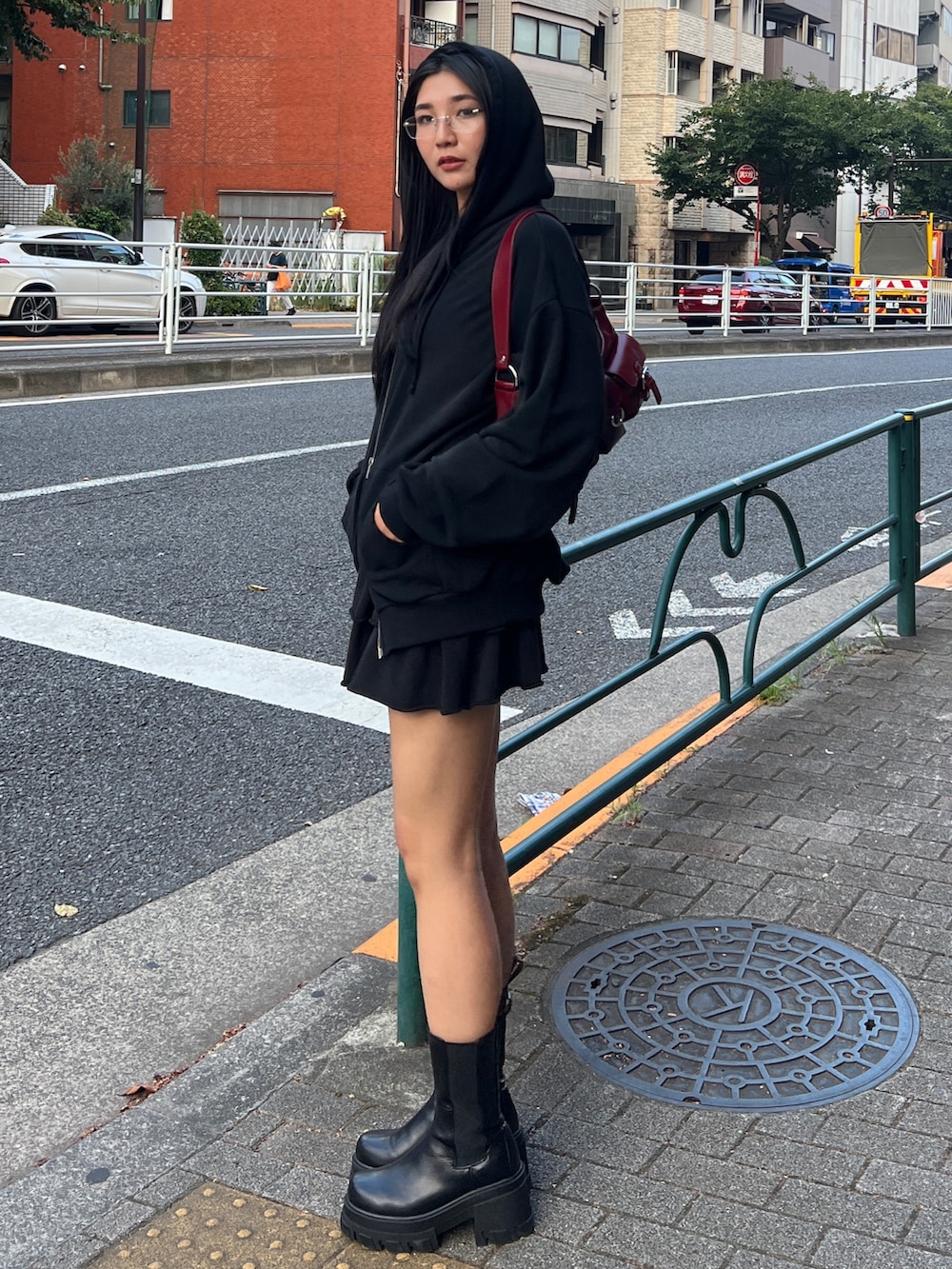 ブラック系のパーカー、ブラック系のスカート、レッド系のハンドバッグを着用したレディースの秋コーディネートの2枚目の写真