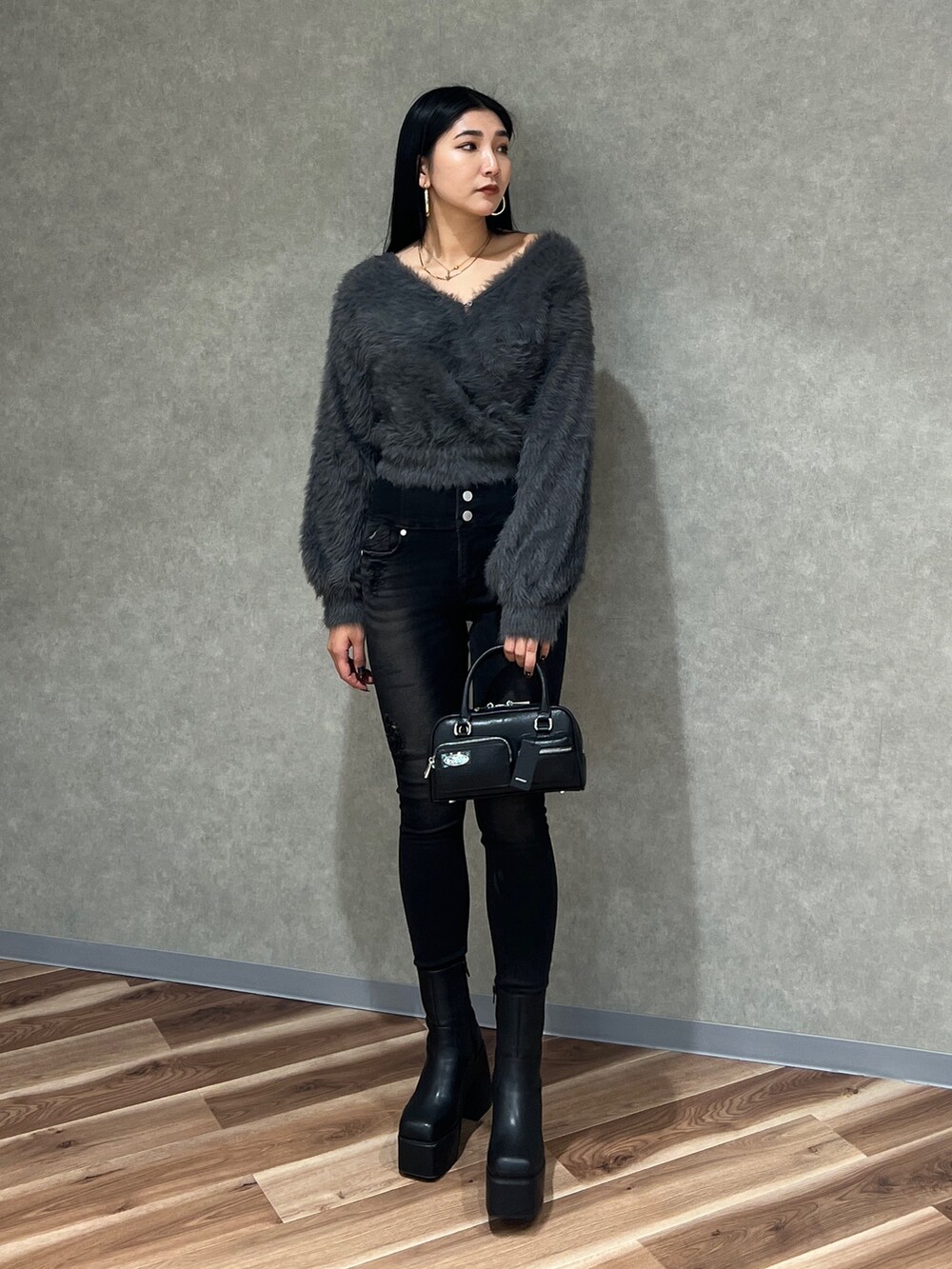 グレー系のニット/セーター、ブラック系のデニムパンツ、ブラック系のブーツを着用したレディースの秋コーディネートの2枚目の写真