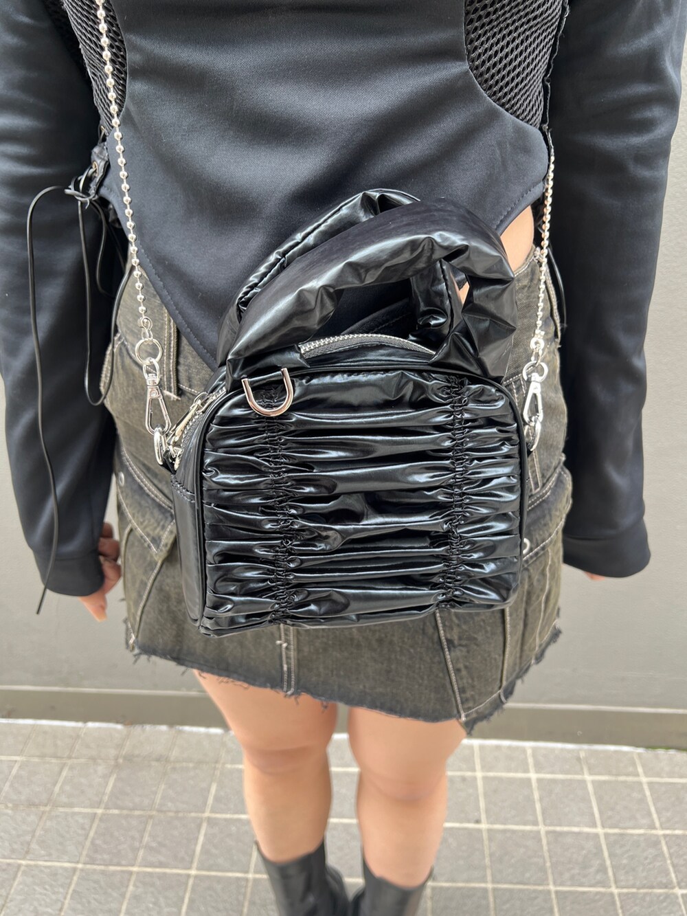 ブラック系のスカート、ブラック系のブーツ、ブラック系のハンドバッグを着用したレディースの春コーディネートの6枚目の写真